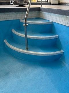 A blue swimming pool with stairs leading up to it