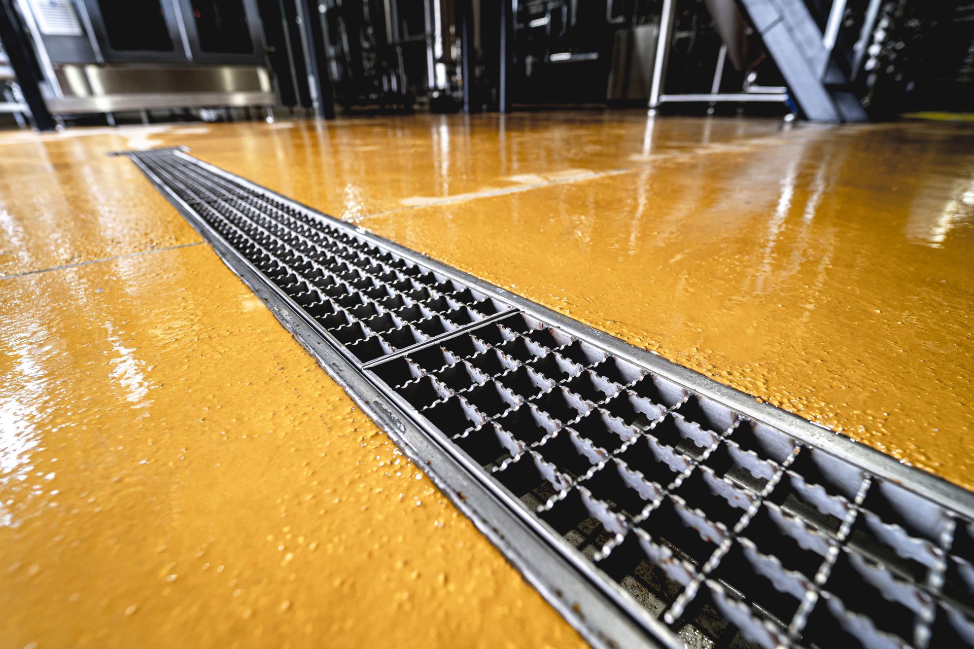 A close up of a drain on a yellow floor.