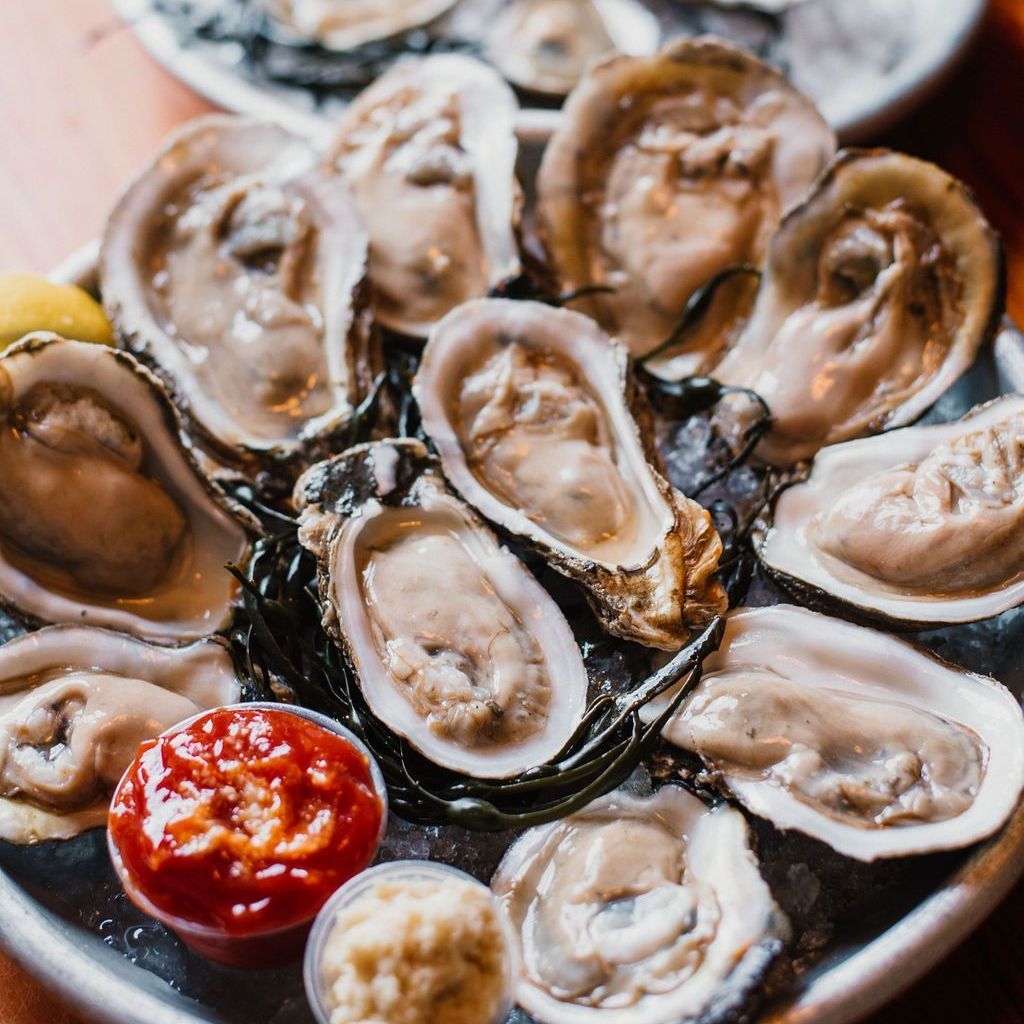 a plate of oysters with sauce on a table .