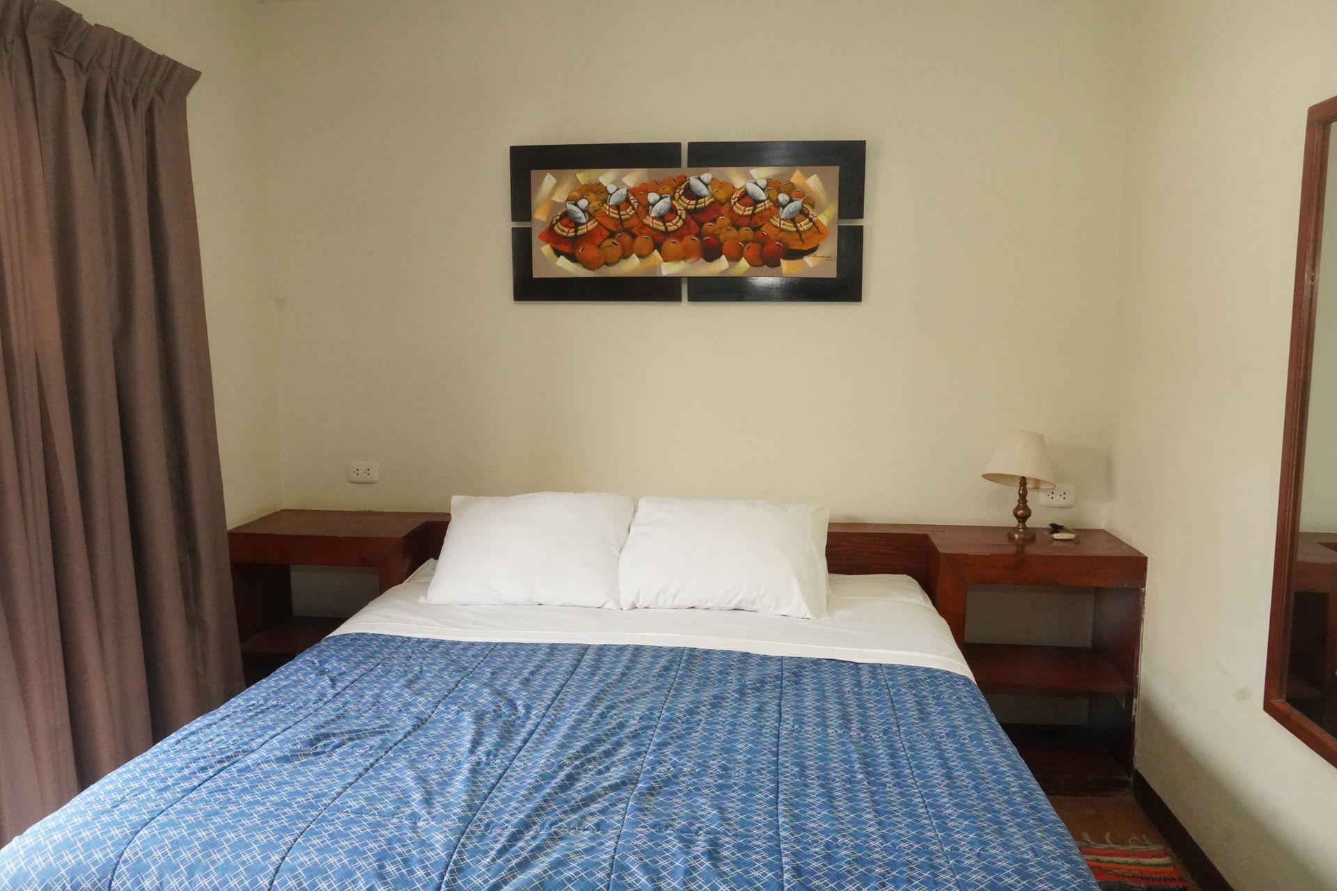 Bedroom with a bed, two nightstands, a painting, a window with curtain, and a mirror.