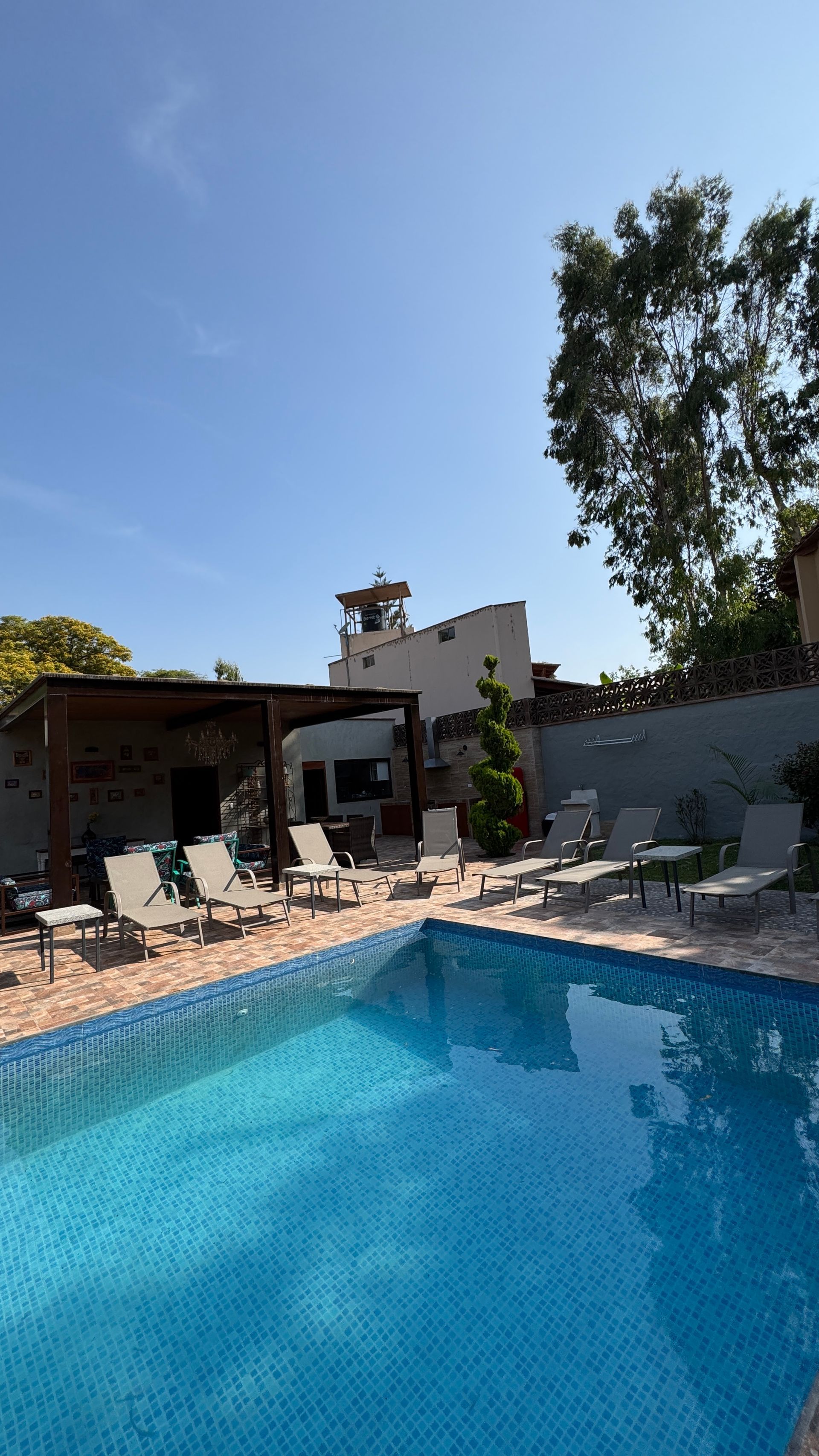 Swimming pool with blue tiles, lounge chairs, and a clear blue sky.