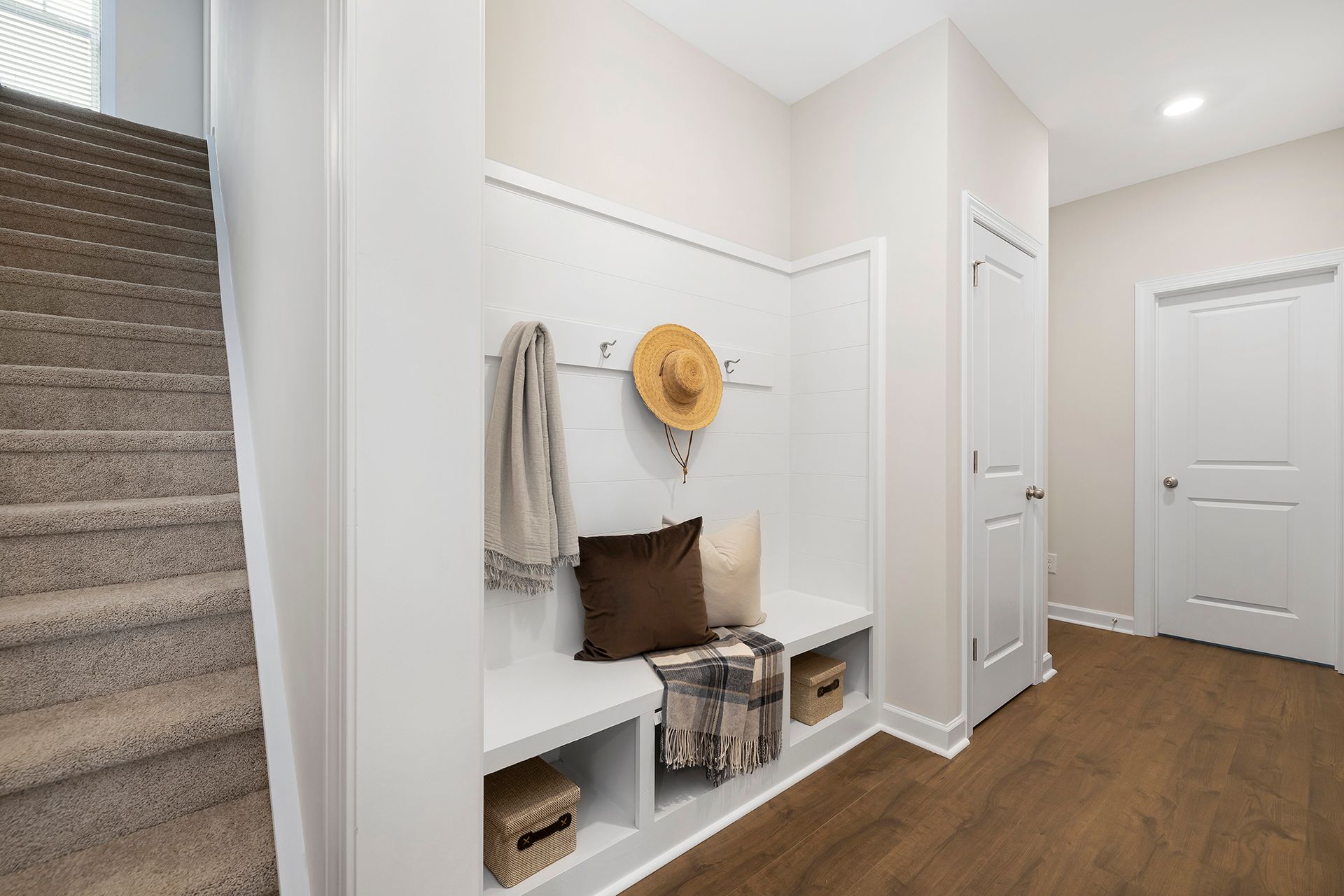 There is a bench in the hallway next to the stairs.