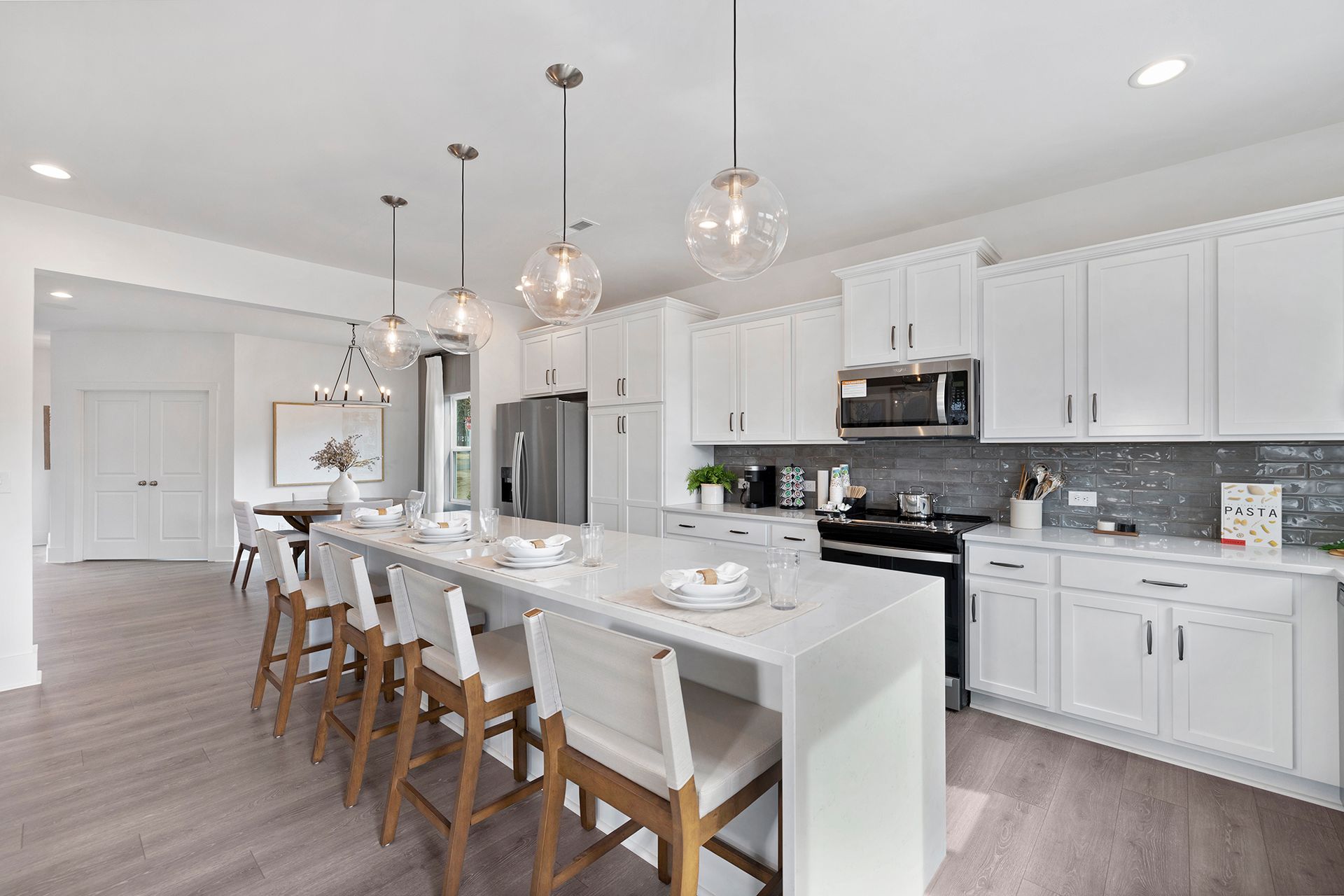 A kitchen with white cabinets , stainless steel appliances , and a large island.