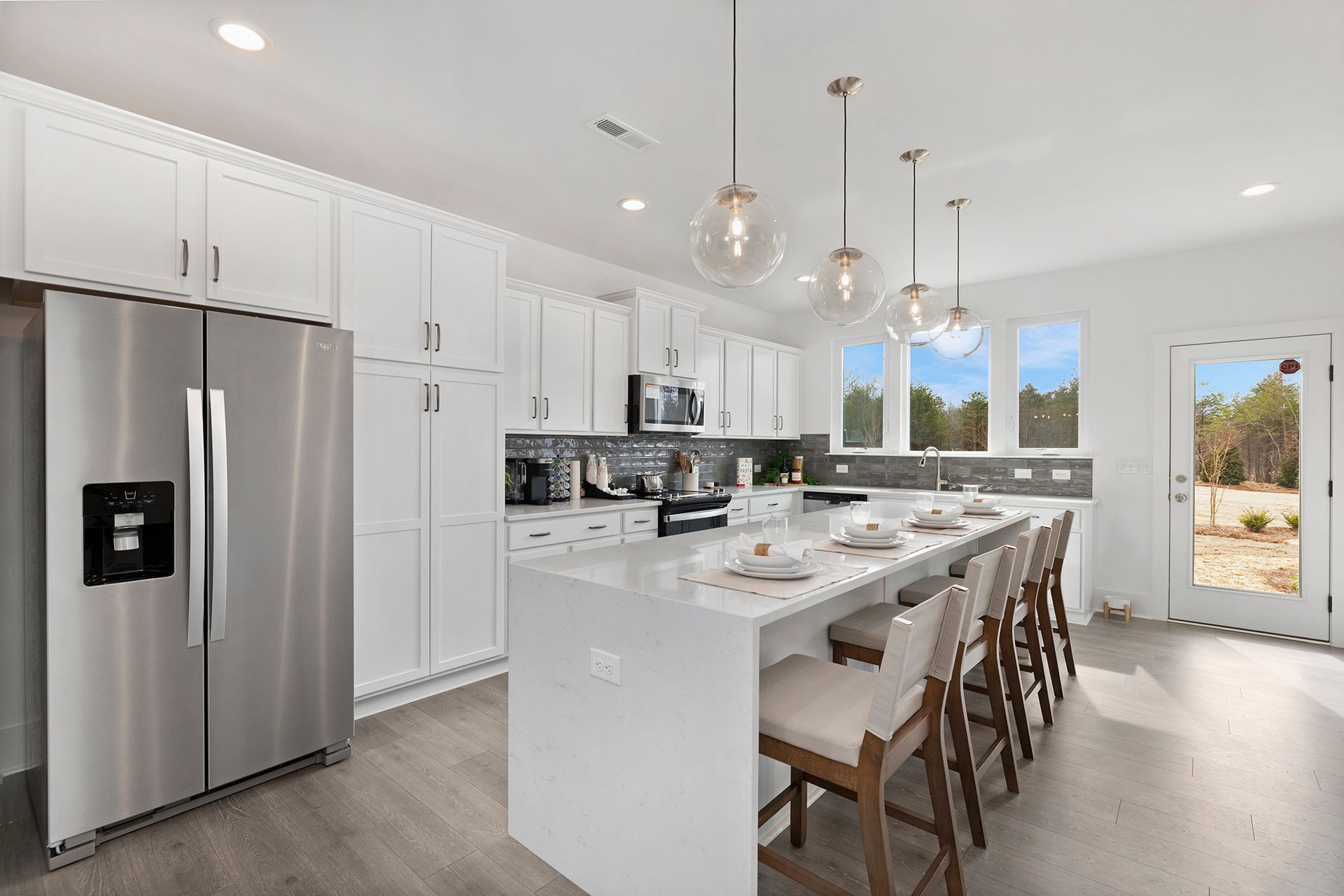 A kitchen with white cabinets , stainless steel appliances , and a large island.