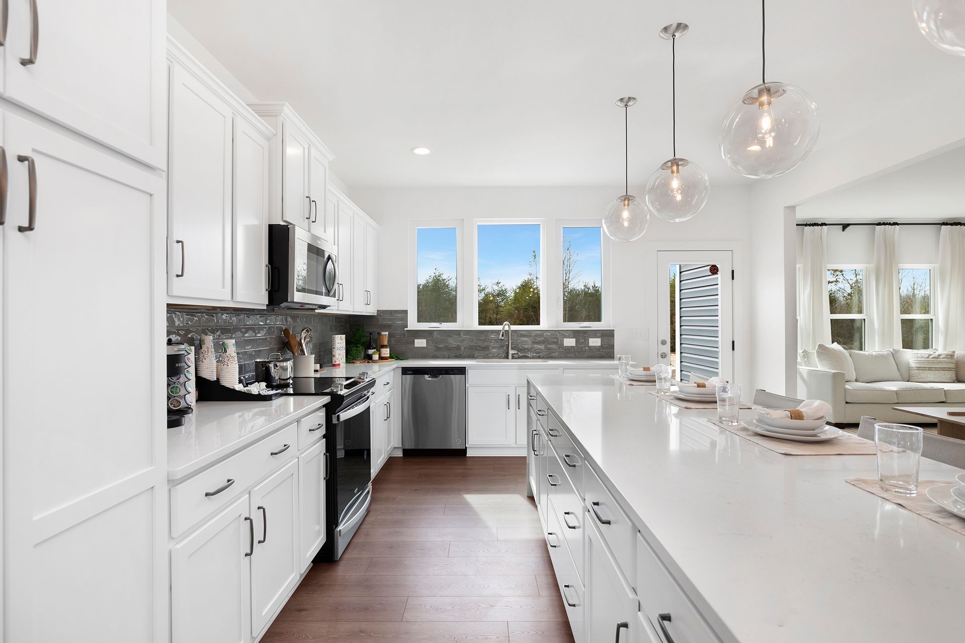 A kitchen with white cabinets , stainless steel appliances , and a large island.