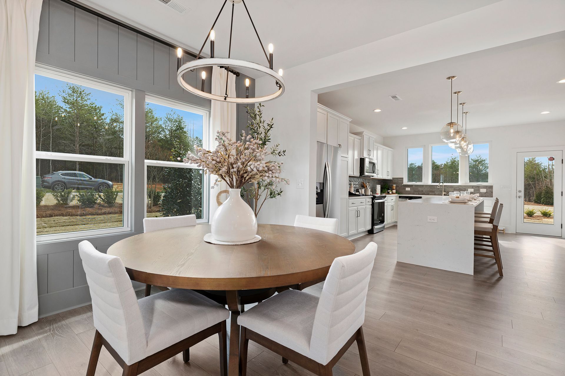 A dining room with a round table and chairs and a chandelier.