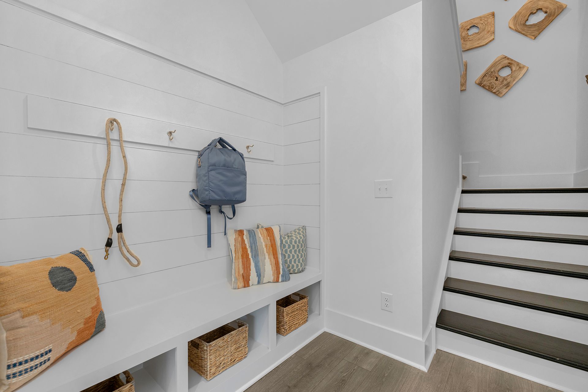 A mud room with a bench and stairs in a house.
