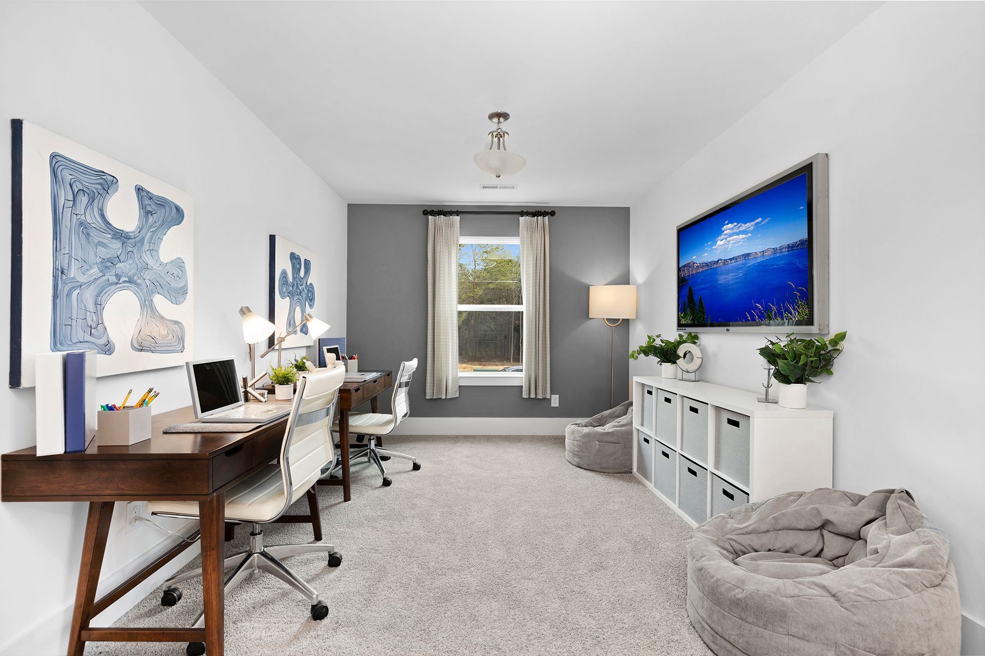 A room with two desks and a television on the wall.