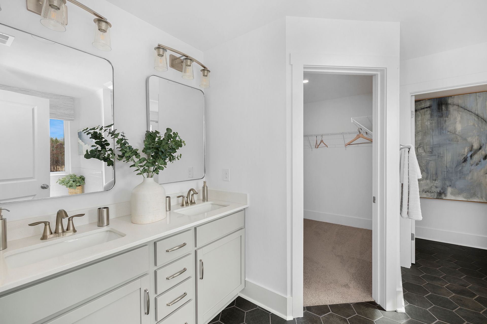 A bathroom with two sinks , a mirror and a walk in closet.