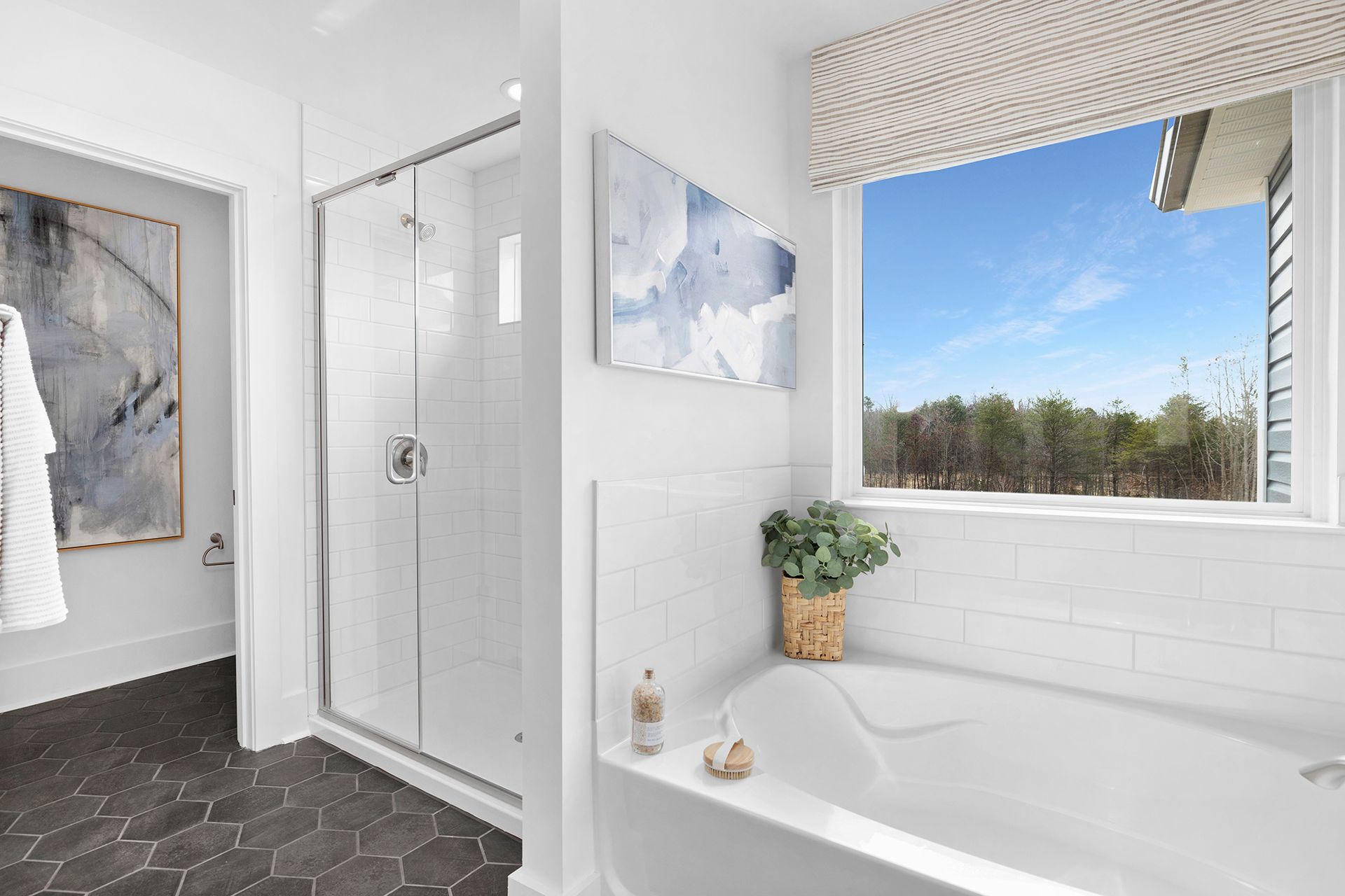 A bathroom with a tub , shower , and window.