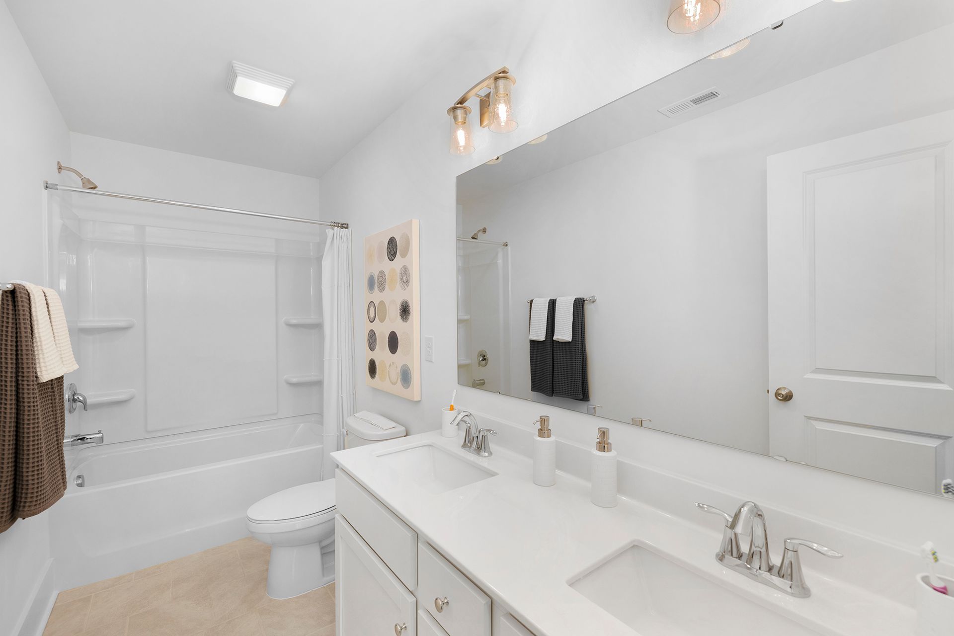 A bathroom with two sinks , a toilet , and a large mirror.