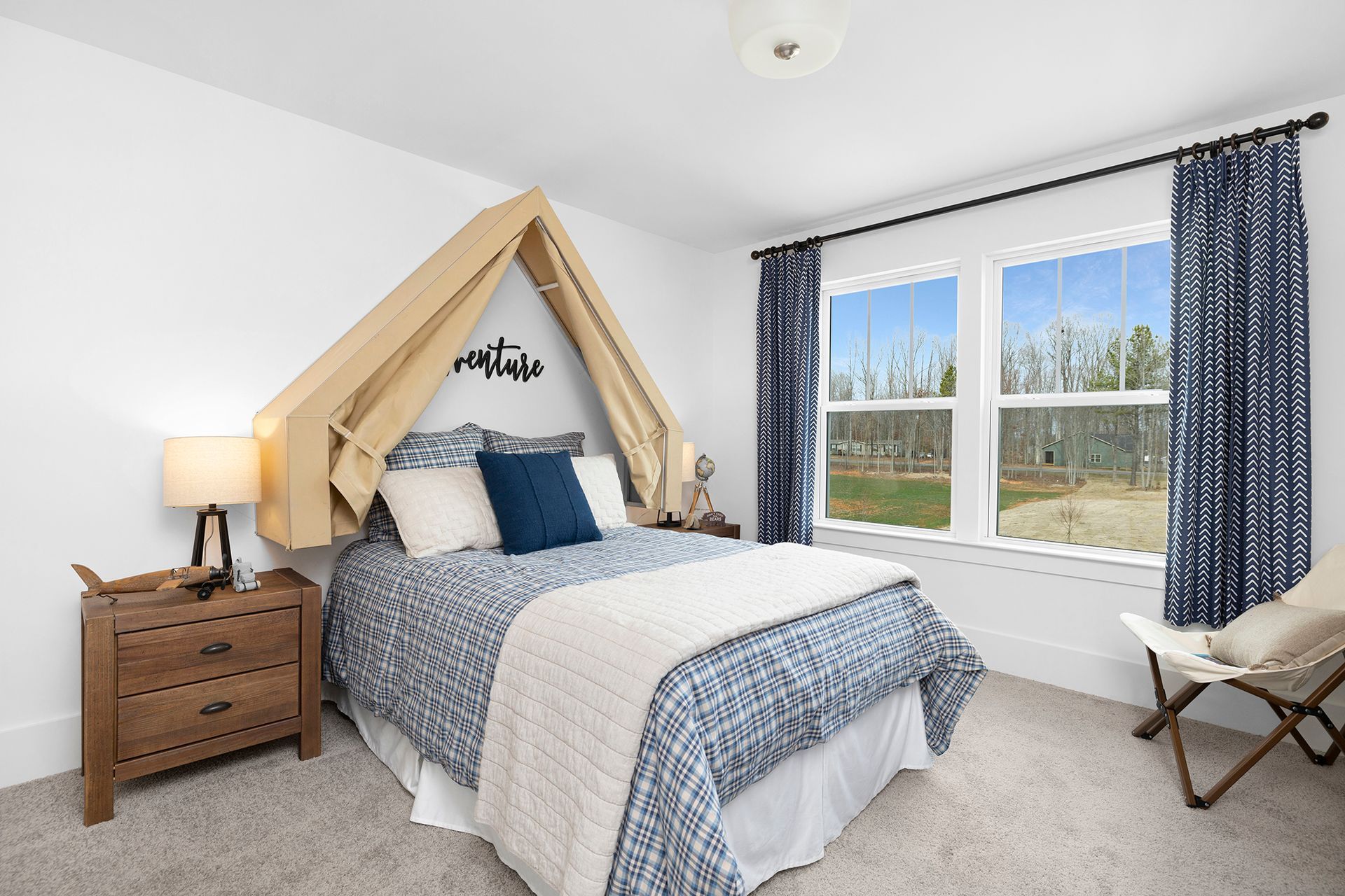 A bedroom with a bed , dresser , nightstand and two windows.