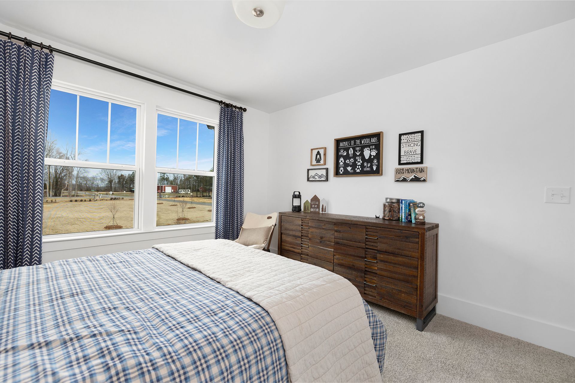 A bedroom with a bed , dresser , and two windows.