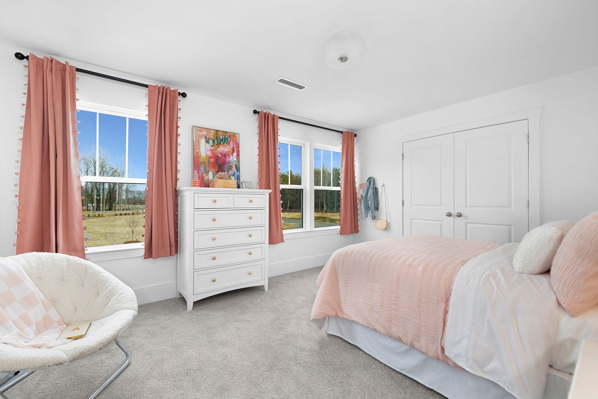A bedroom with a bed , dresser , chair and two windows.