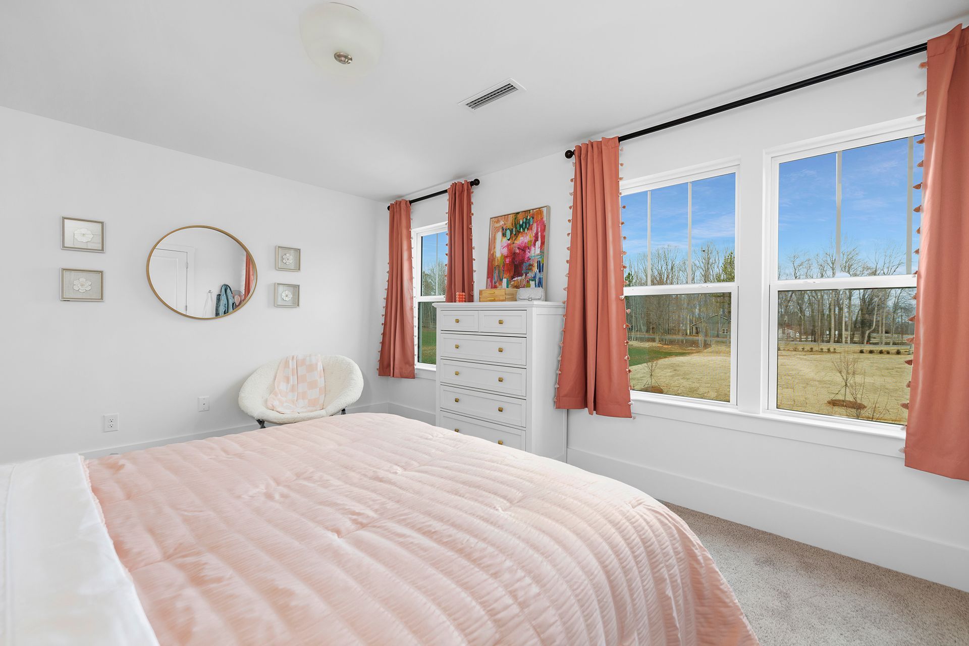 A bedroom with a bed , nightstand , chair and mirror.