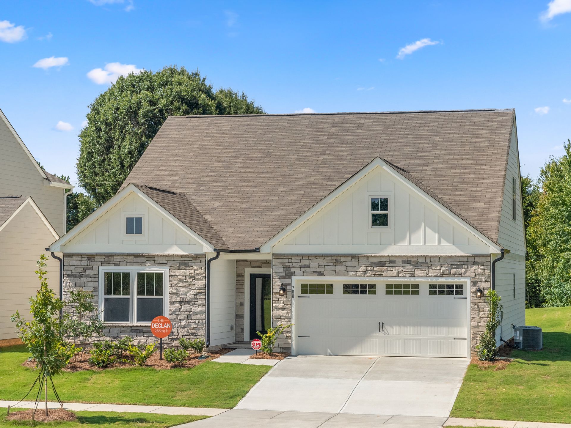 A white house with a brown roof and a white garage door