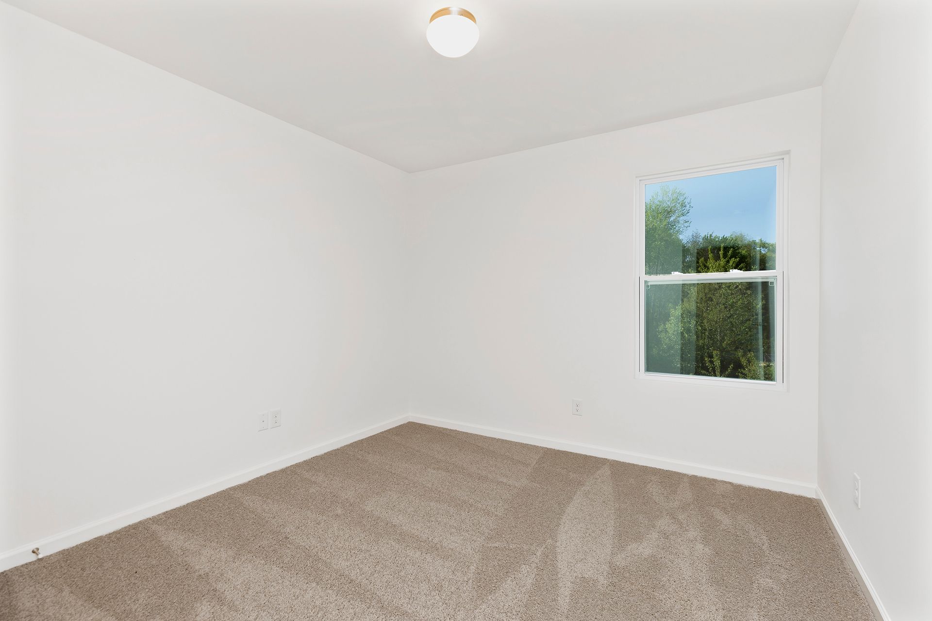 An empty bedroom with a window and a ceiling fan.