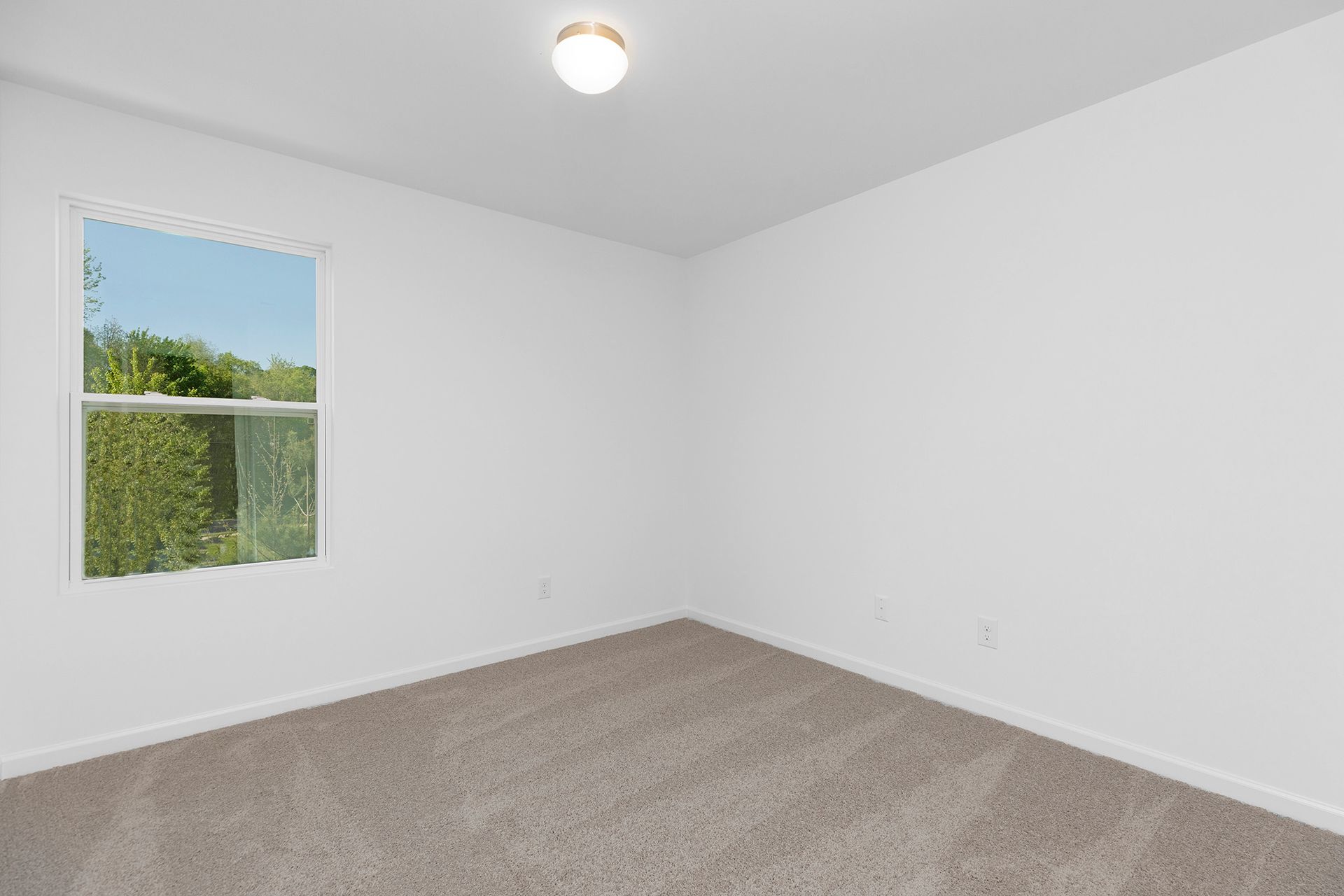 An empty bedroom with a window and a light on the ceiling.