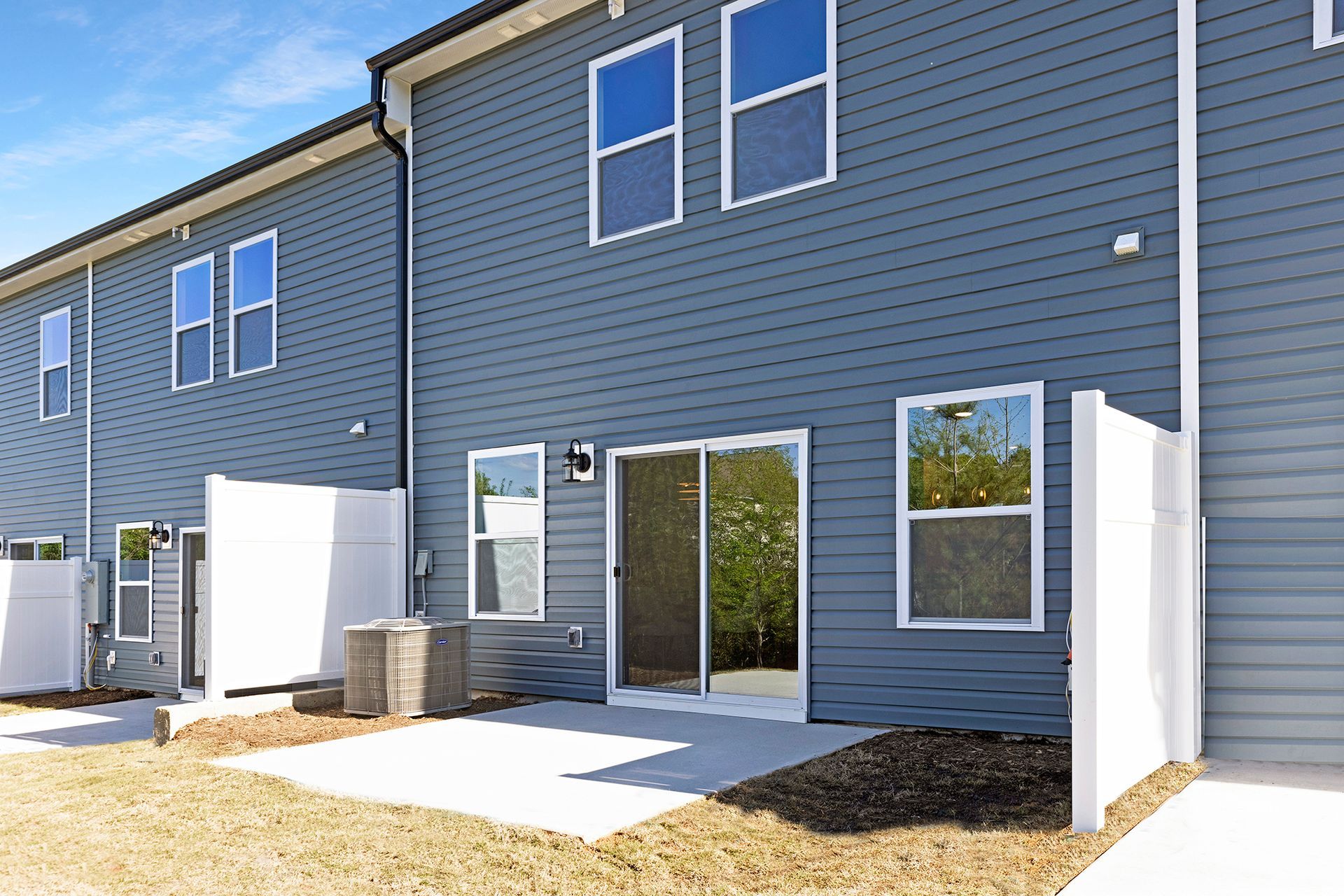 The back of a house with a patio and sliding glass doors.