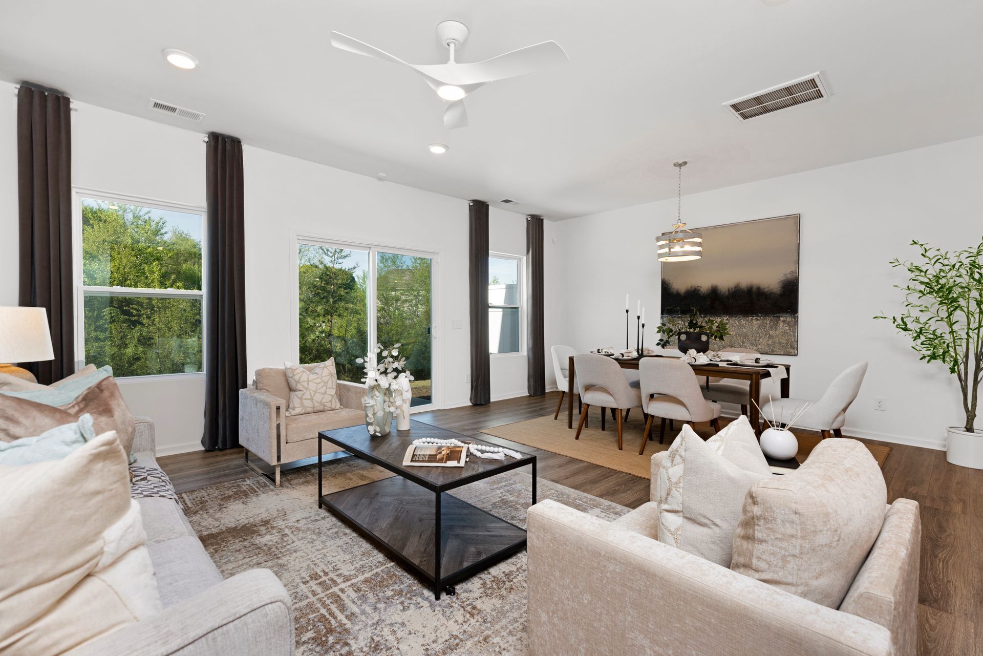 A living room with a couch , chairs , a coffee table and a ceiling fan.