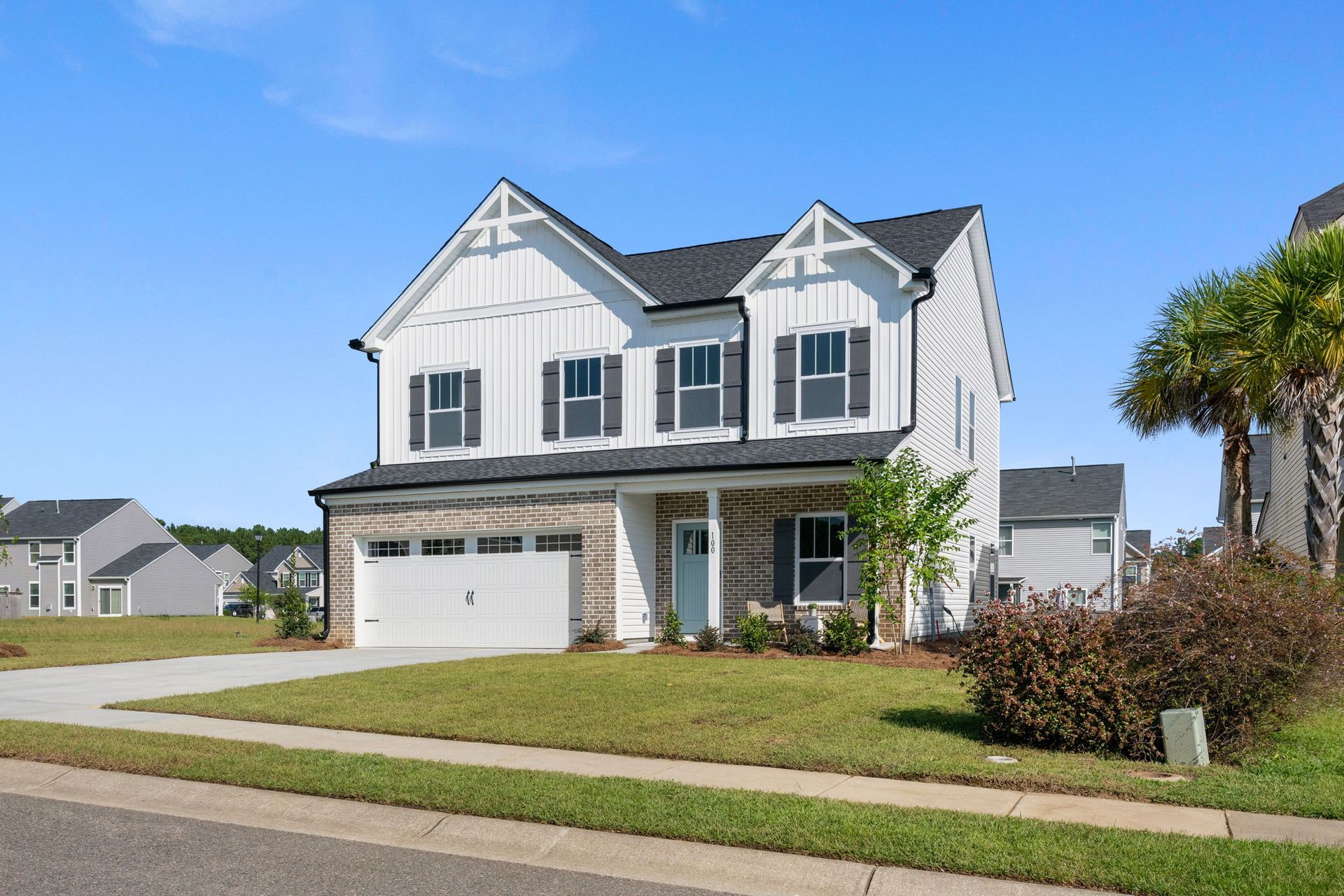 A large white house with black shutters is sitting on top of a lush green lawn.