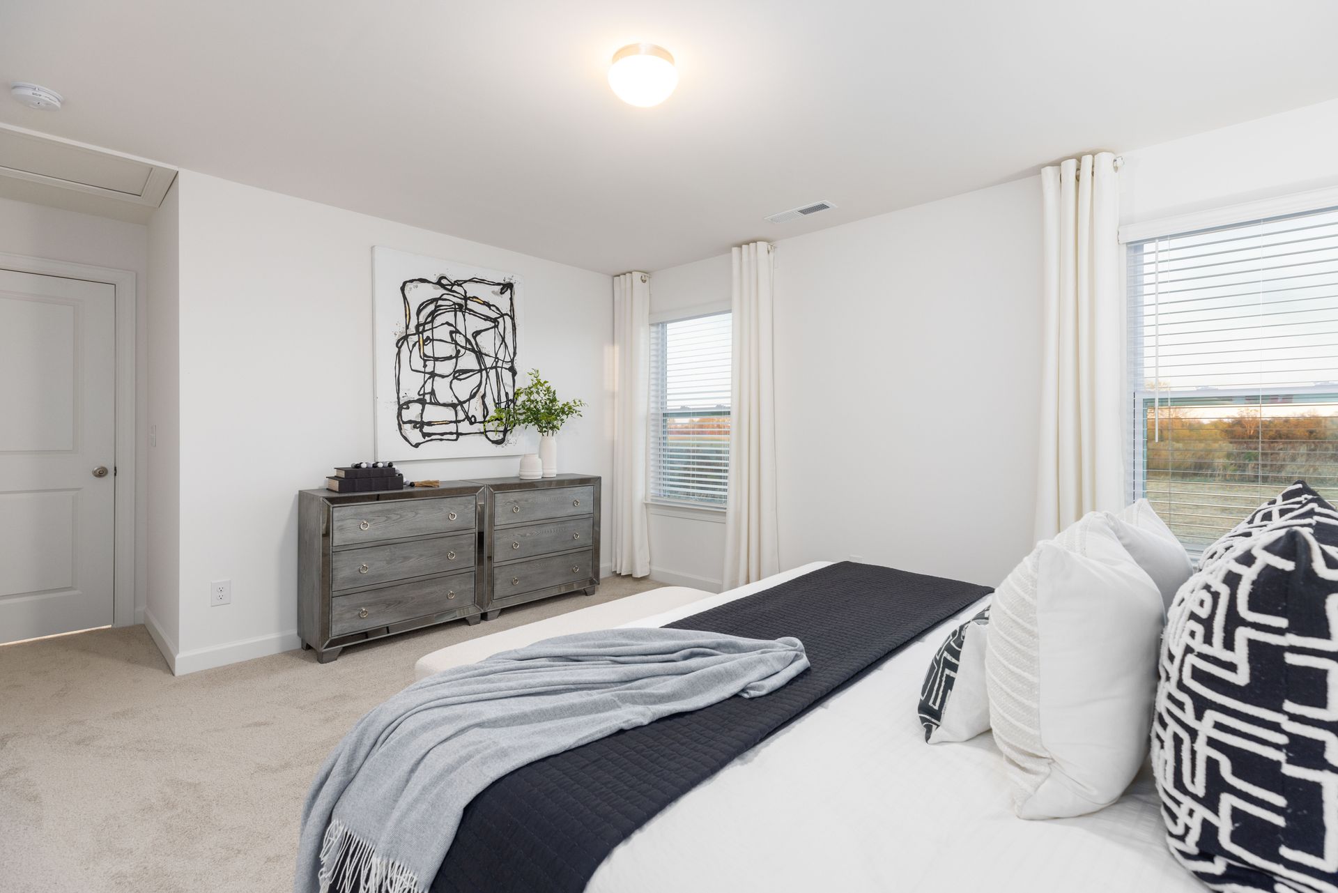 A bedroom with a king size bed , dresser , and window.