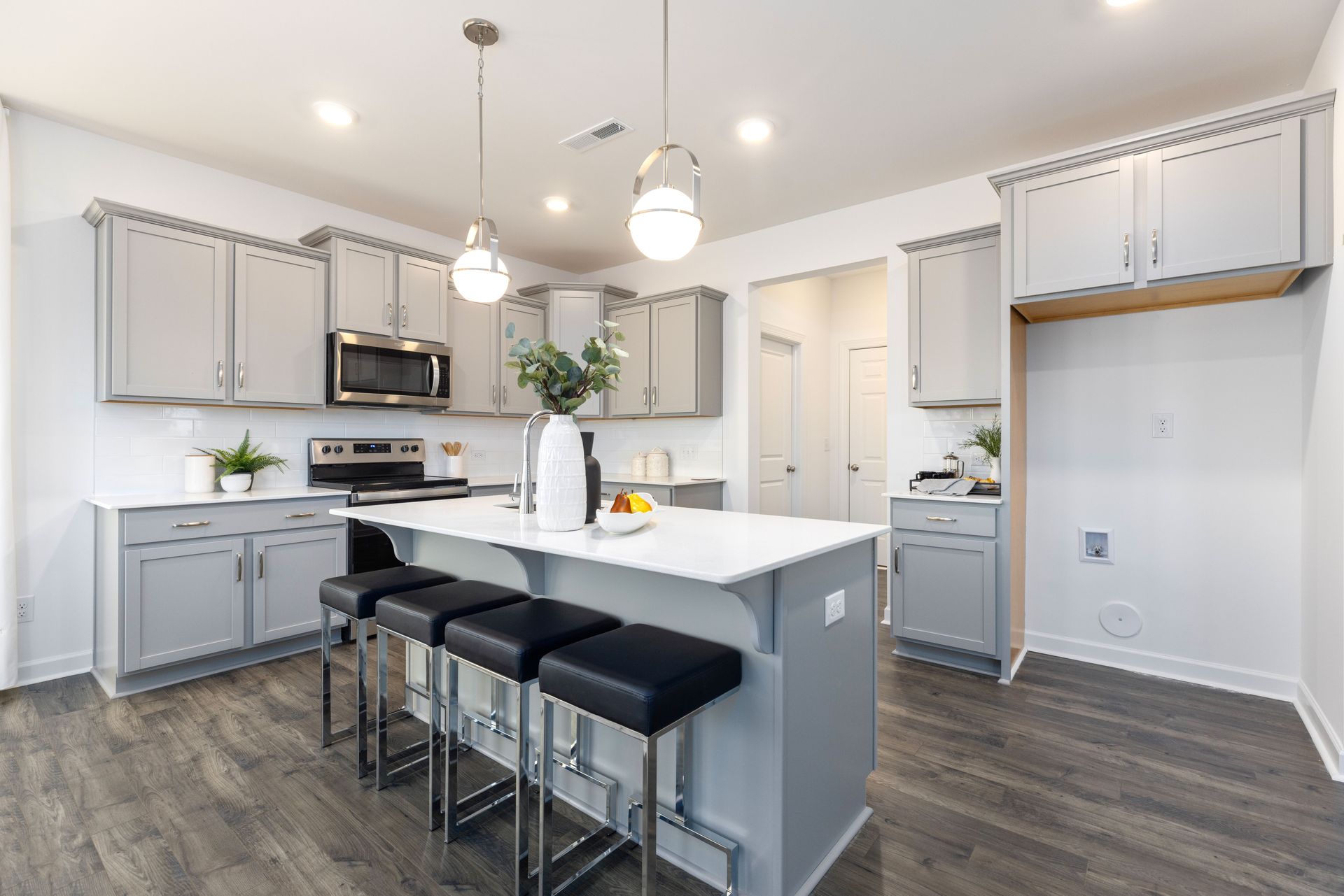 A kitchen with gray cabinets and a large island with stools.