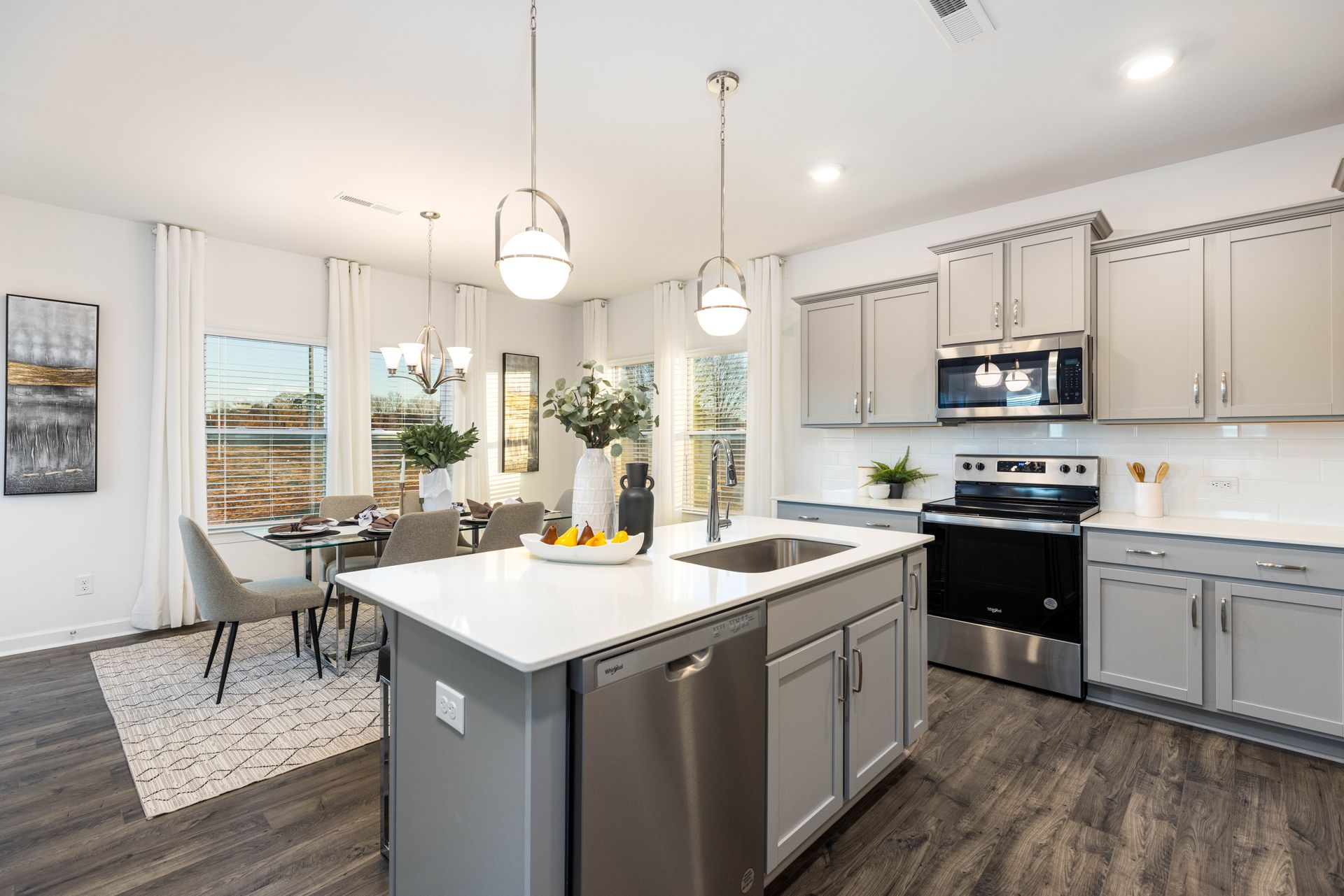 A kitchen in a model home with stainless steel appliances and gray cabinets.