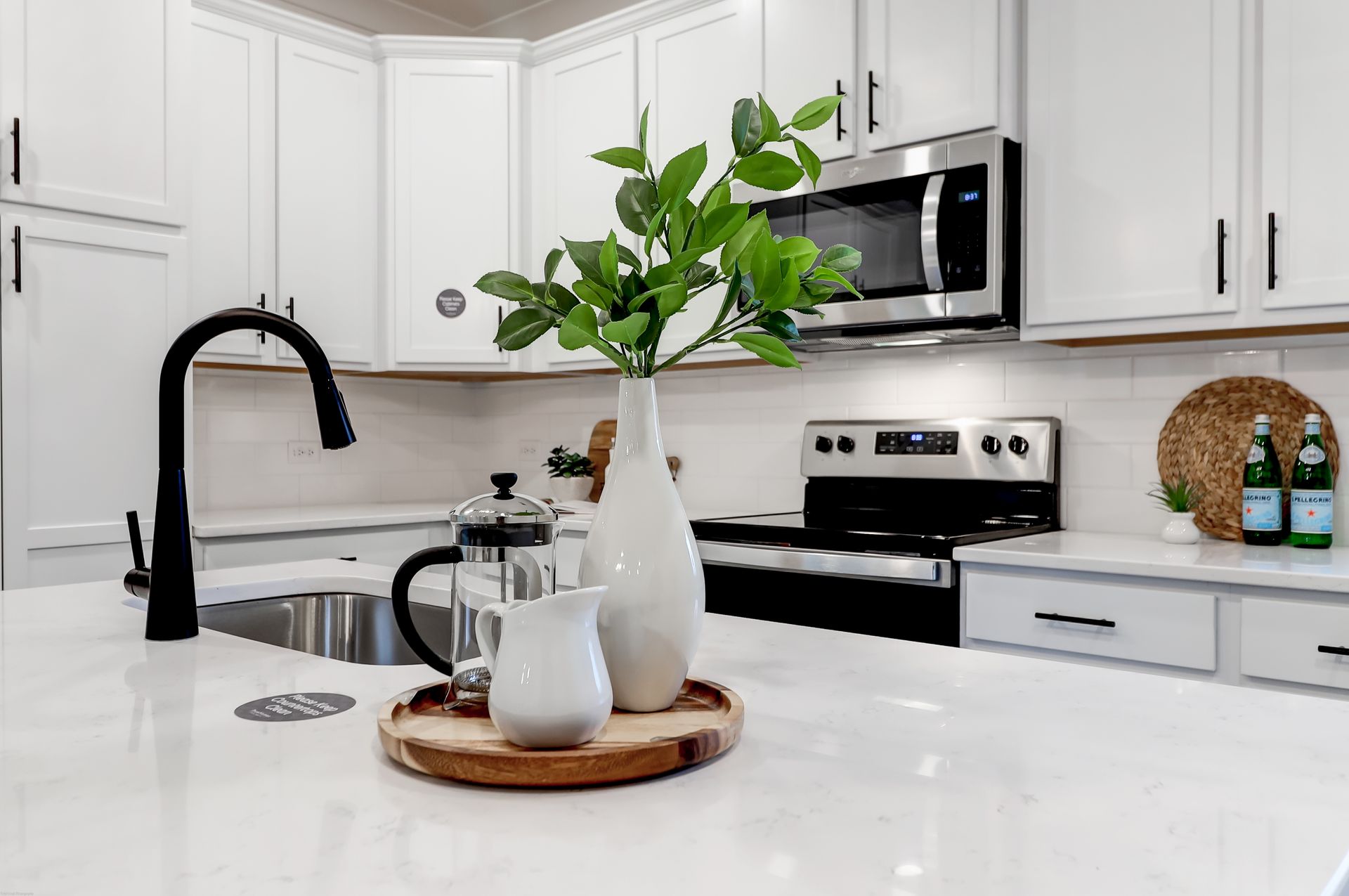 A kitchen with white cabinets , stainless steel appliances , a sink , and a microwave.