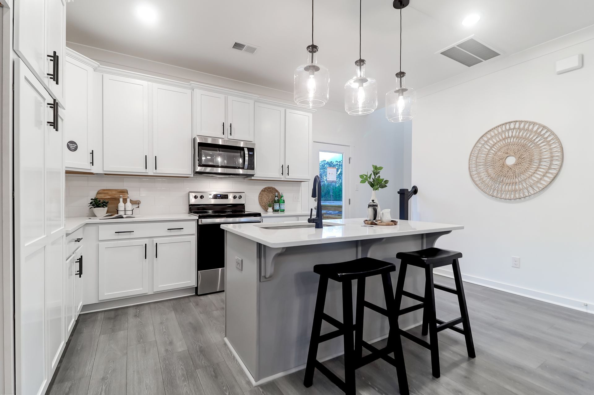A kitchen with white cabinets , stainless steel appliances , and a large island.