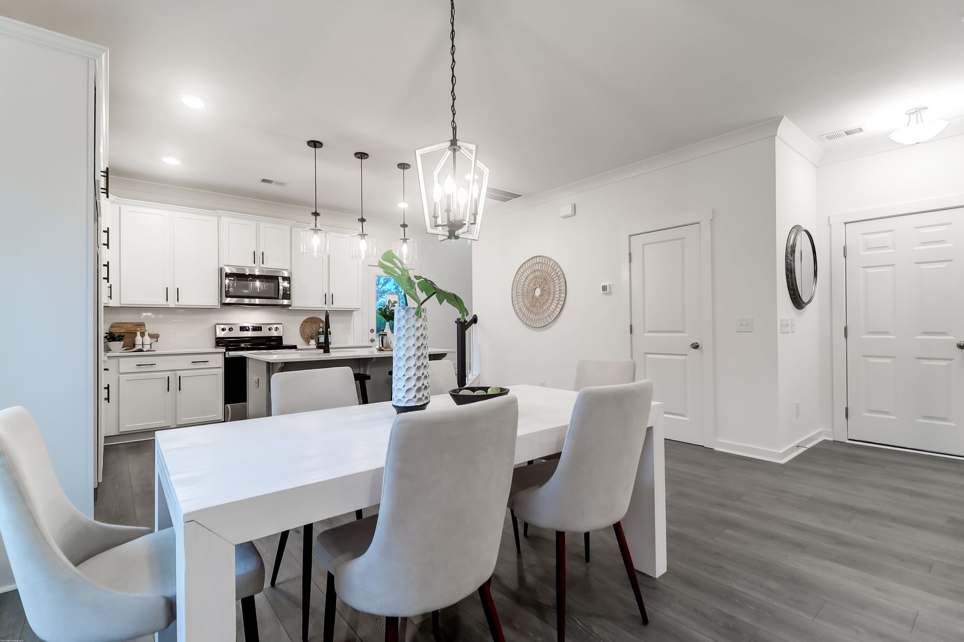 A dining room table and chairs in a house with a kitchen in the background.