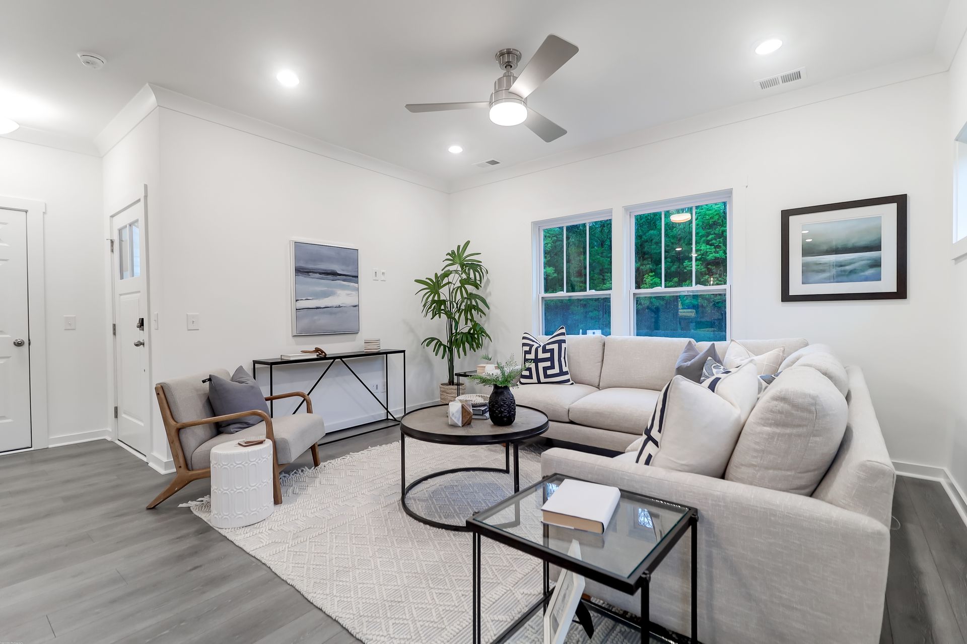 A living room with a couch , chair , coffee table and ceiling fan.