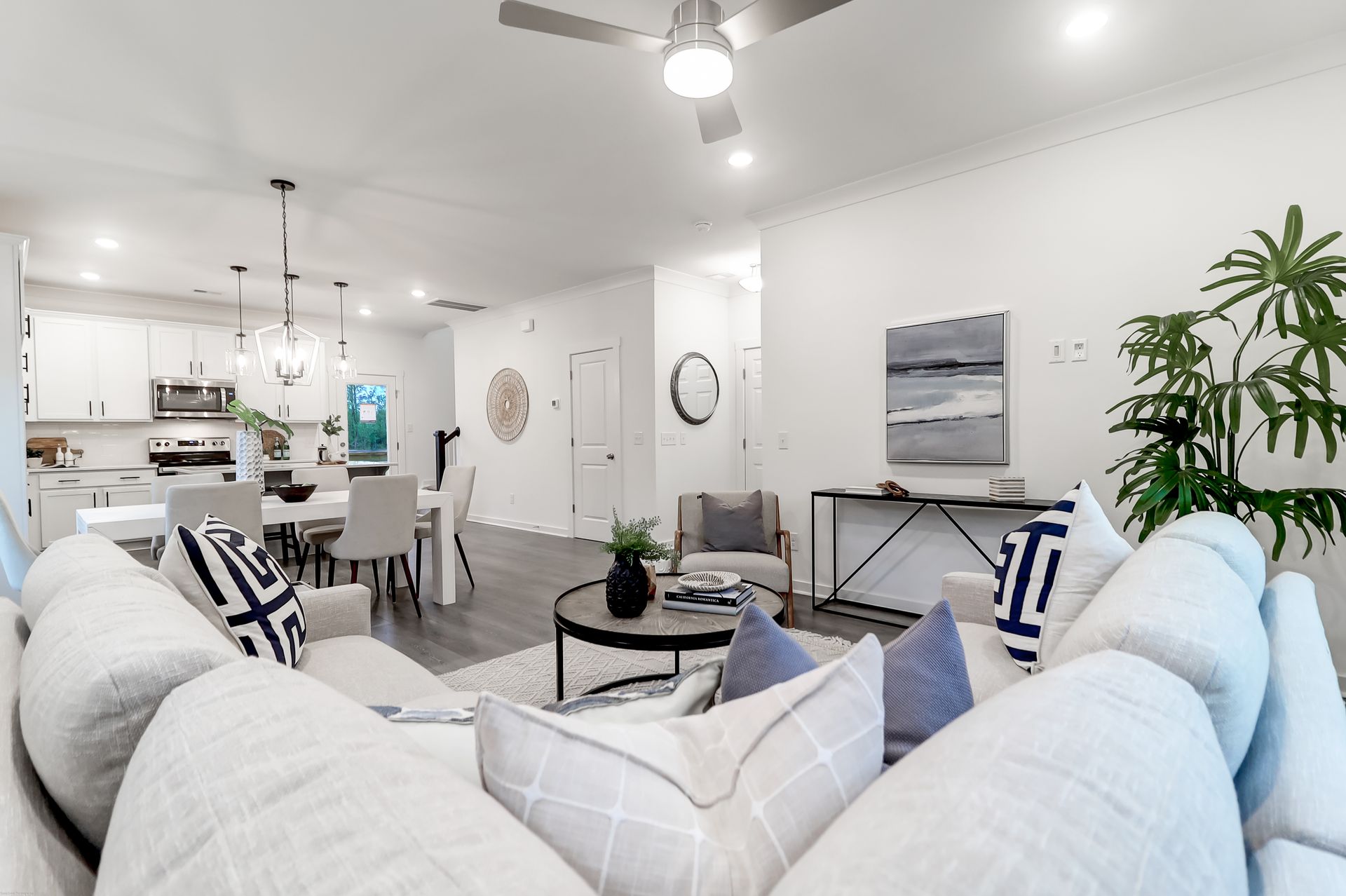 A living room with white furniture and a ceiling fan