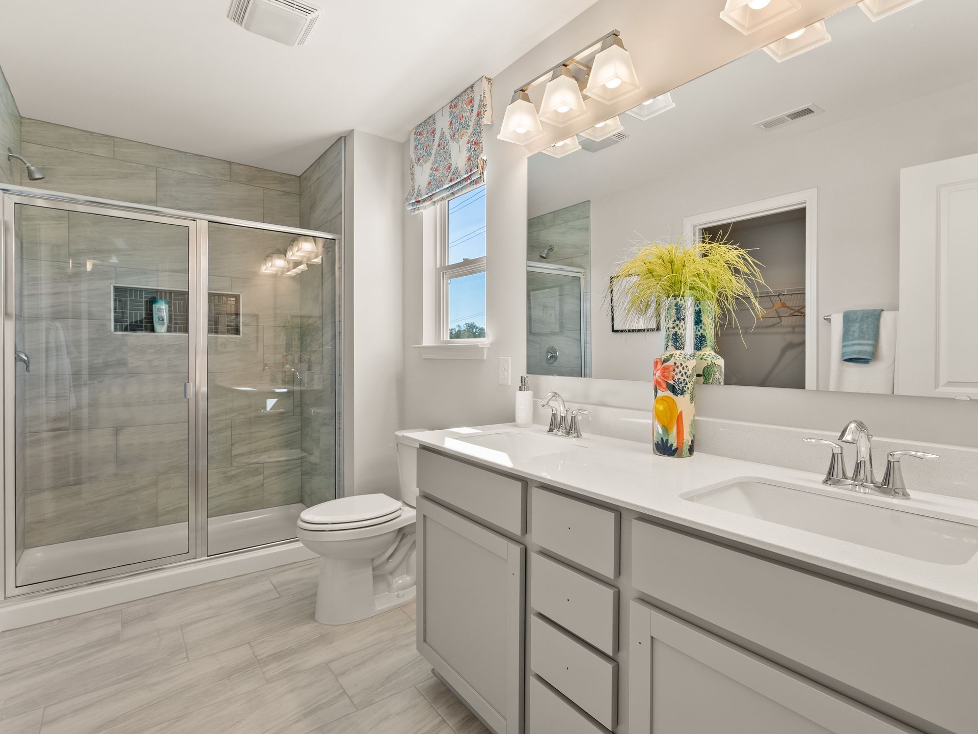 A bathroom with two sinks , a toilet , and a walk in shower.