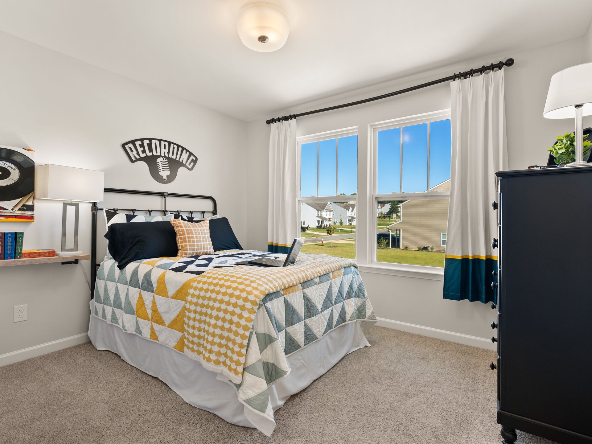 A bedroom with a bed , dresser , and window.