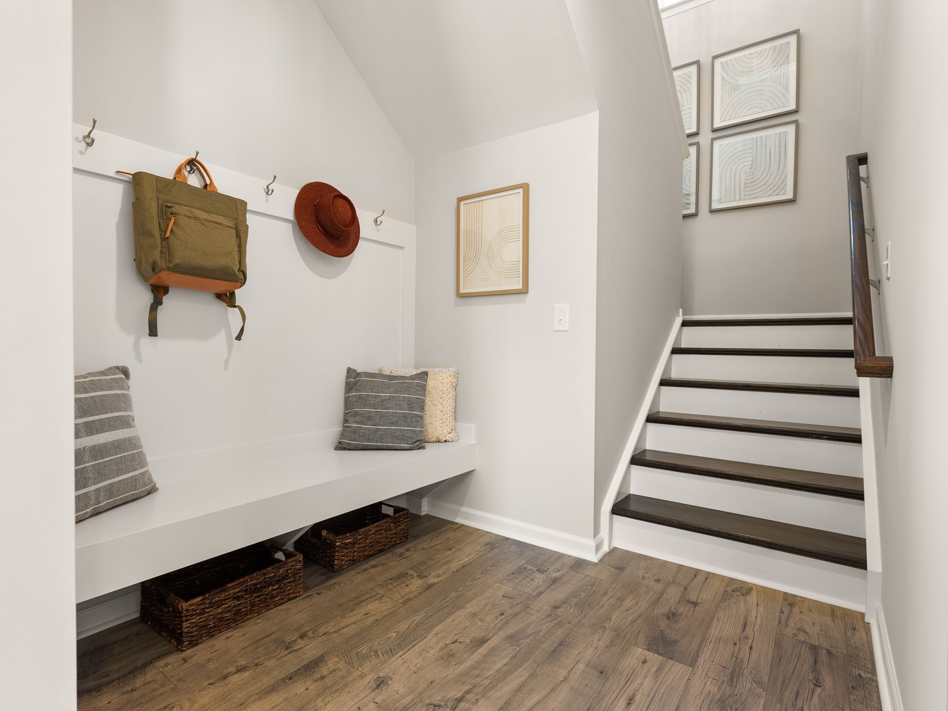 A hallway with a bench and stairs leading up to the second floor.