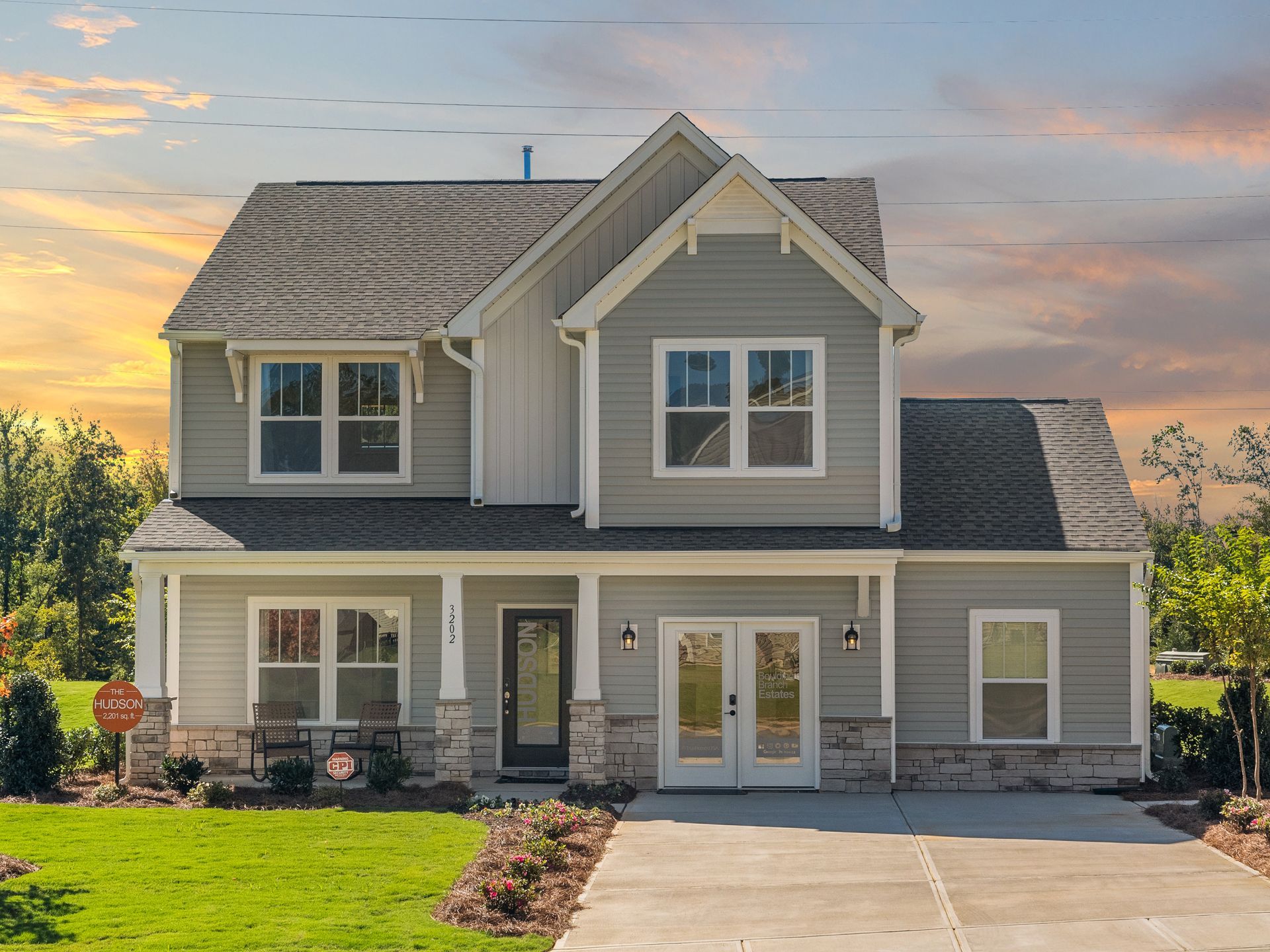 A large gray house with a lot of windows and a concrete driveway.