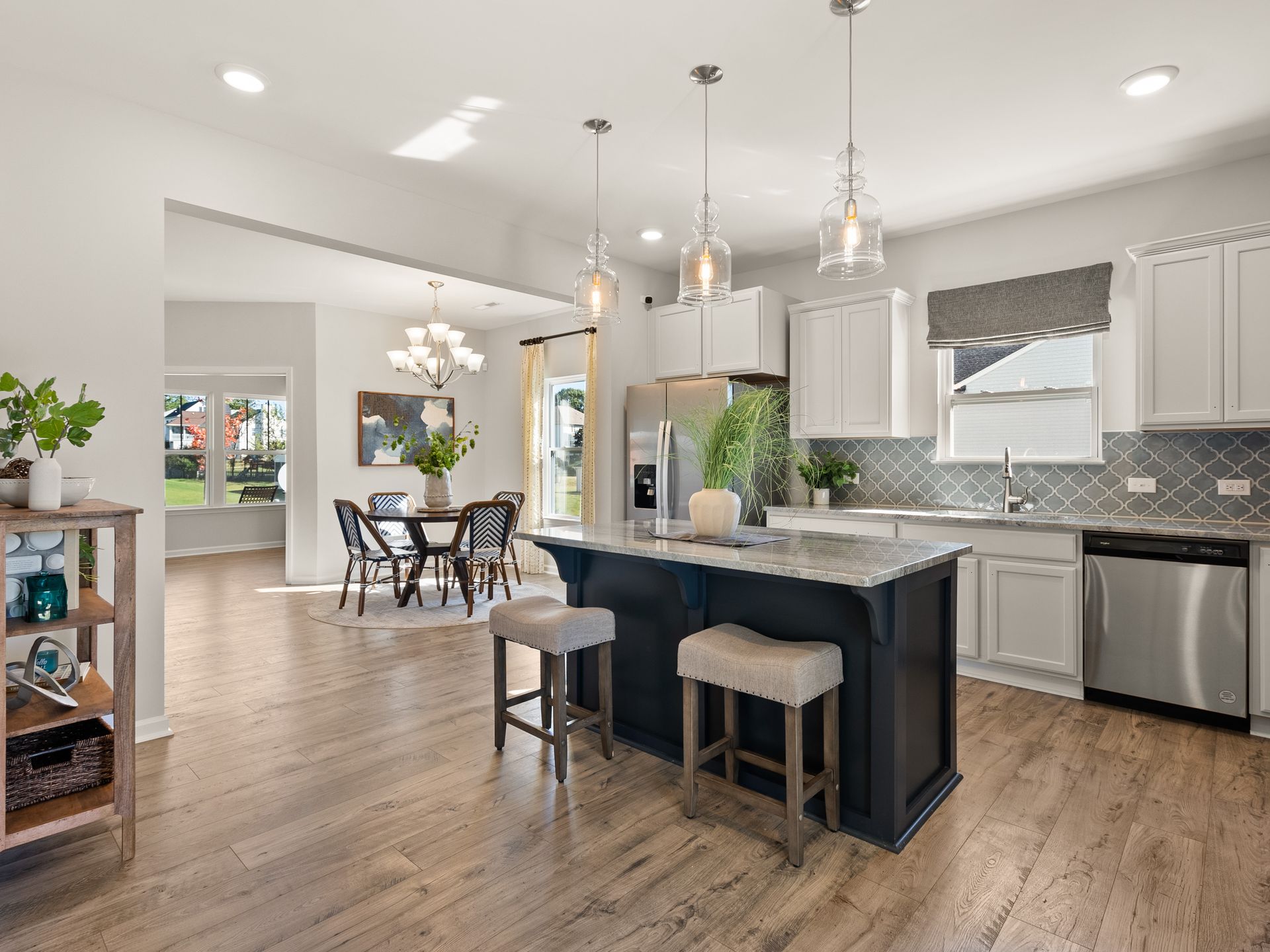 A kitchen with a large island , stainless steel appliances , white cabinets and hardwood floors.