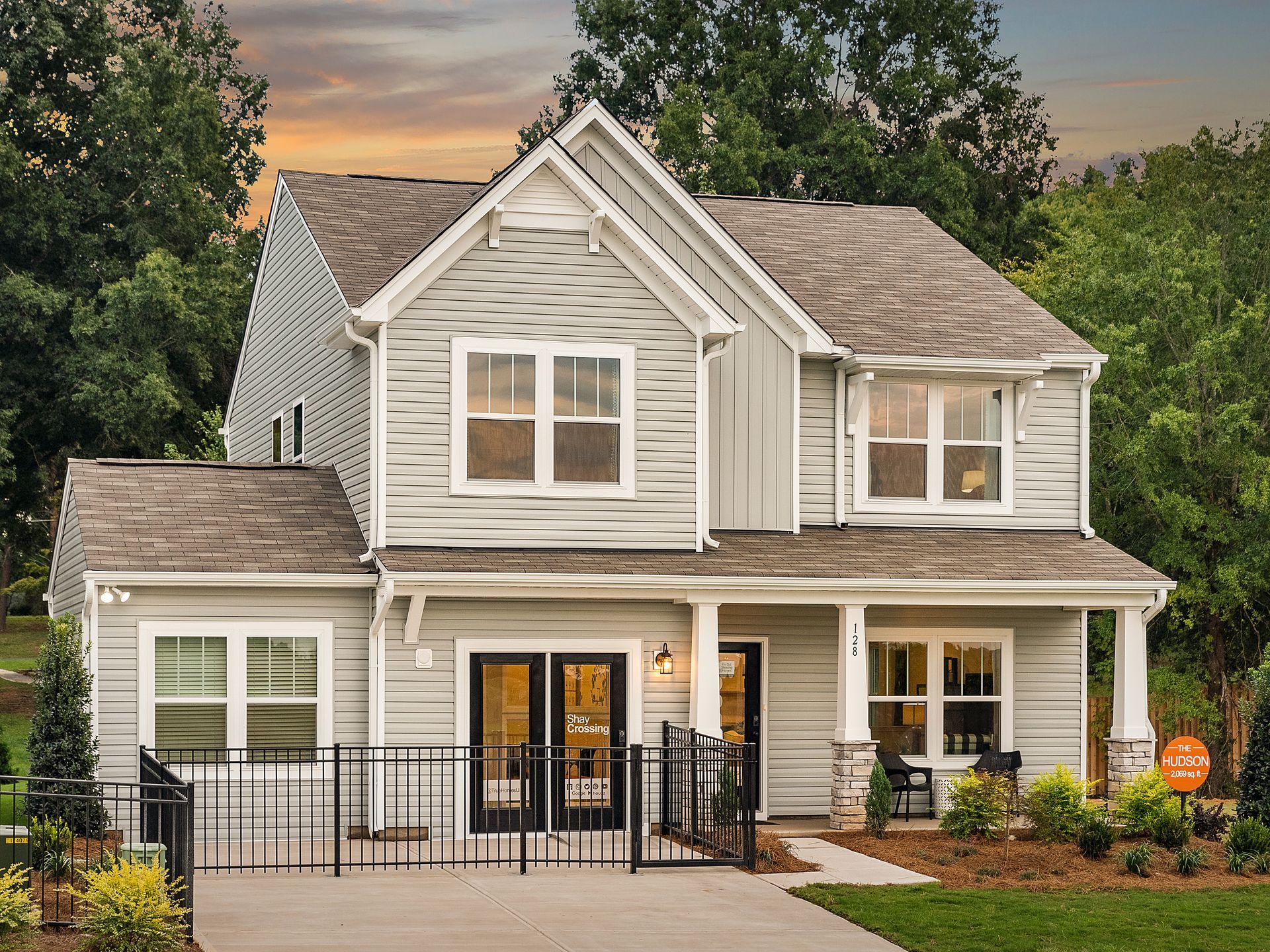 A white house with a brown roof and a fence in front of it.