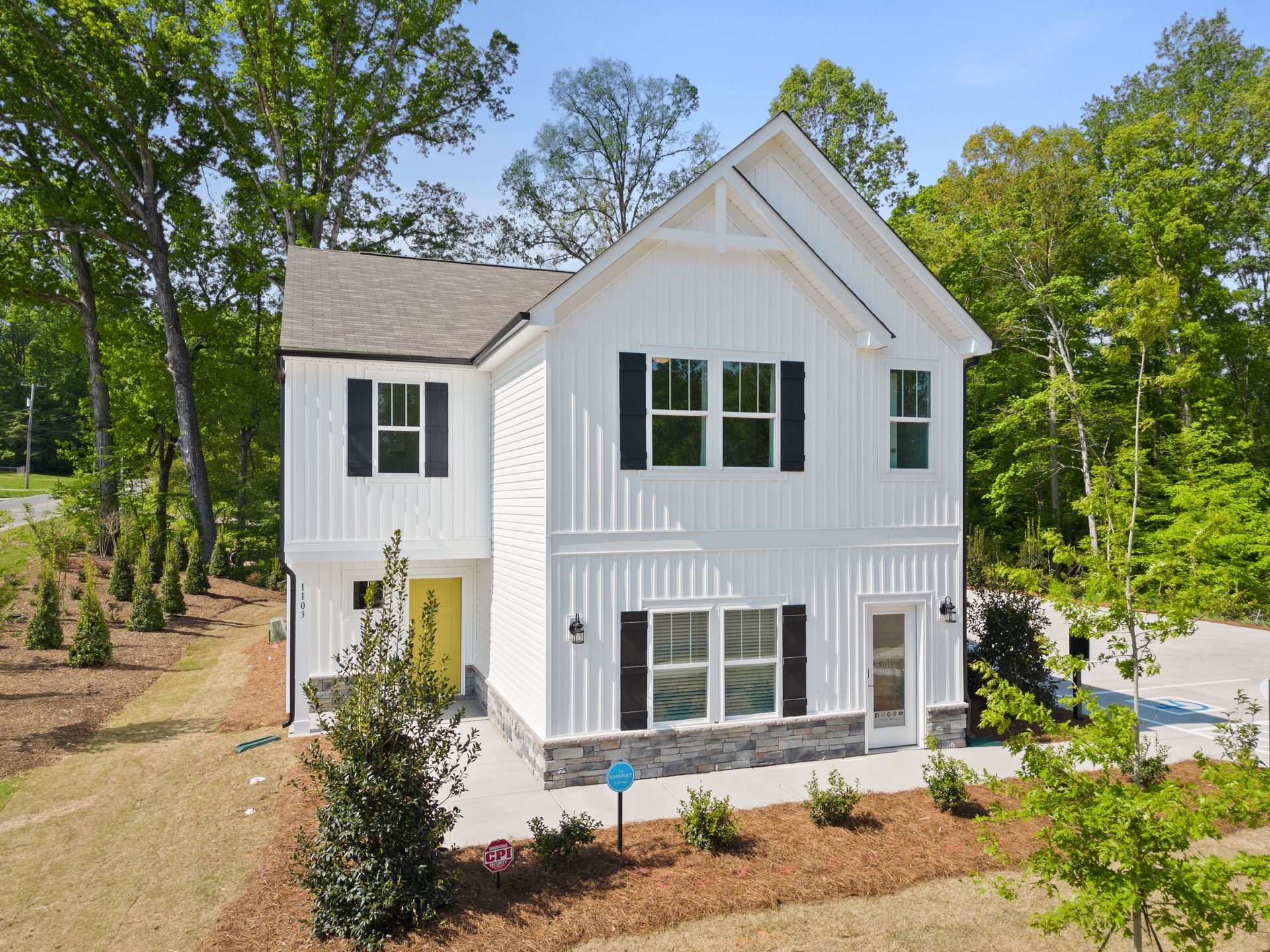 An aerial view of a white house with black shutters