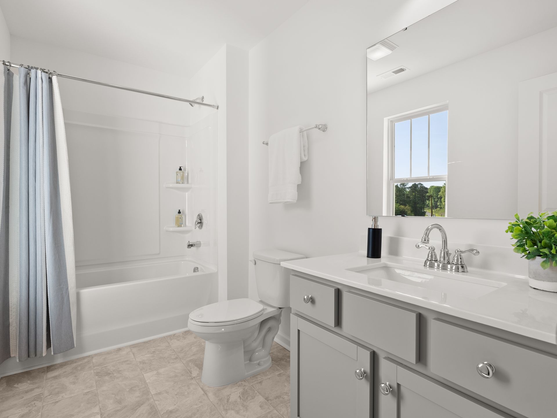 A bathroom with a toilet , sink , tub and mirror.