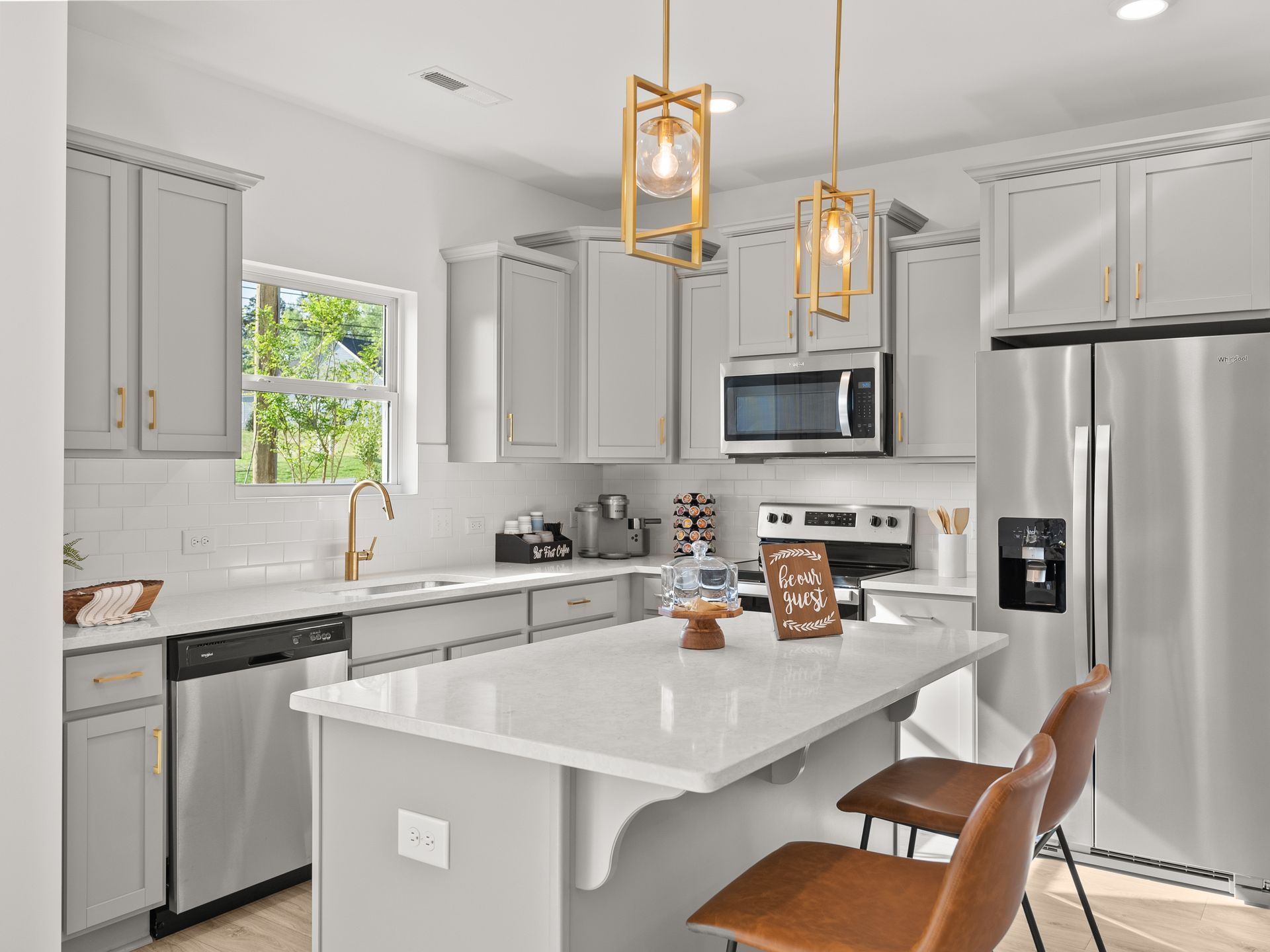 A kitchen with white cabinets , stainless steel appliances , and a large island.
