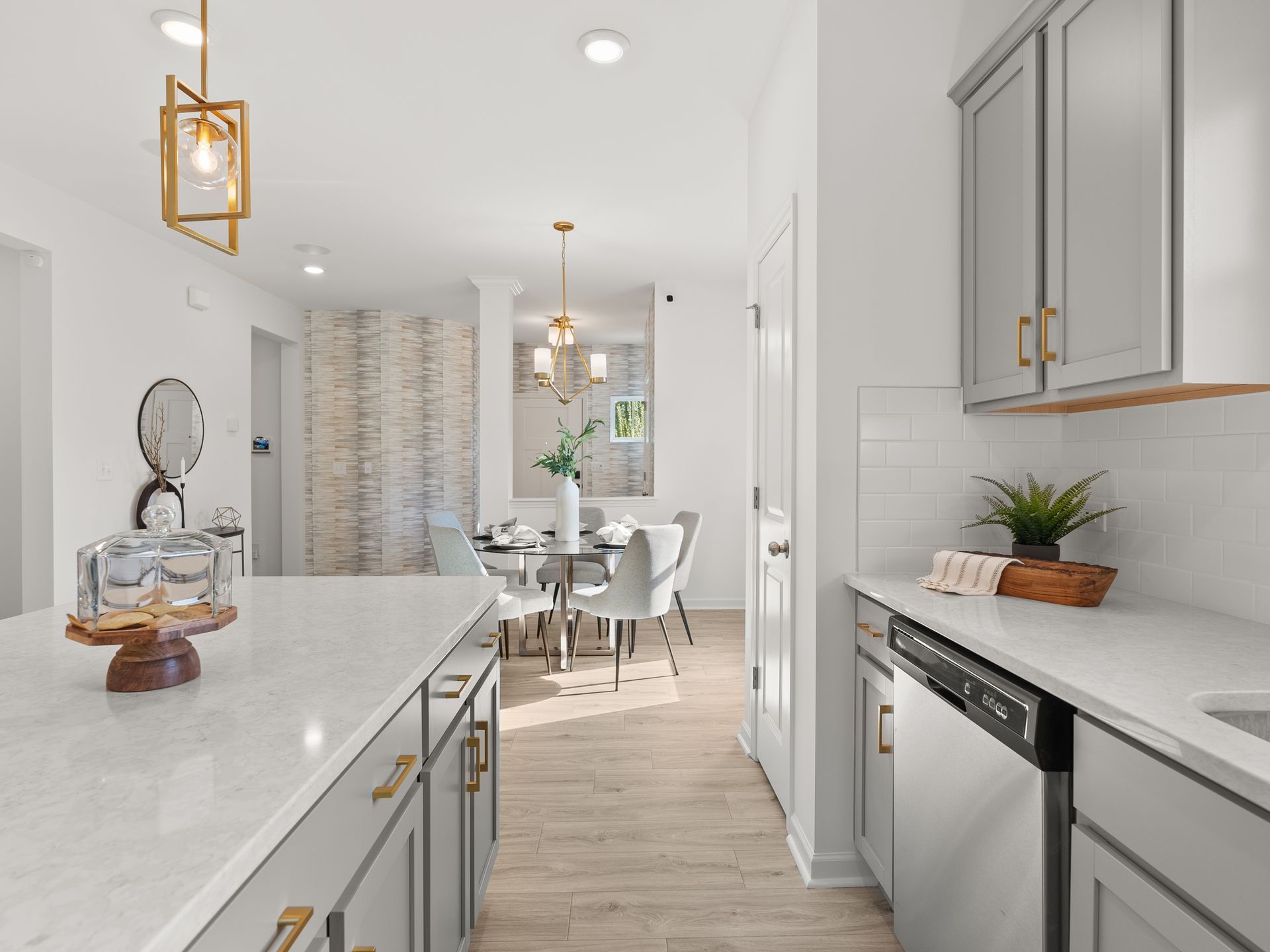 A kitchen with white cabinets and a dining room in the background.