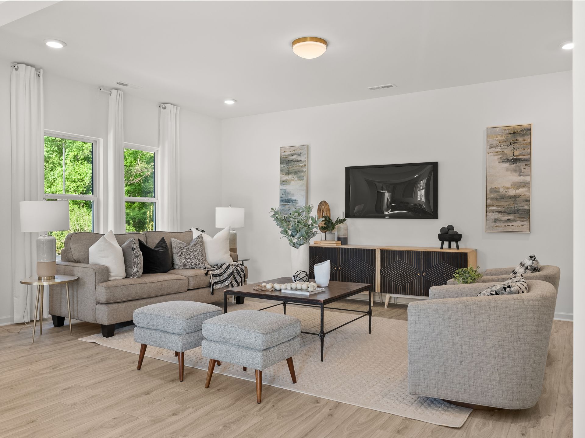 A living room with a couch , chairs , ottomans and a television.
