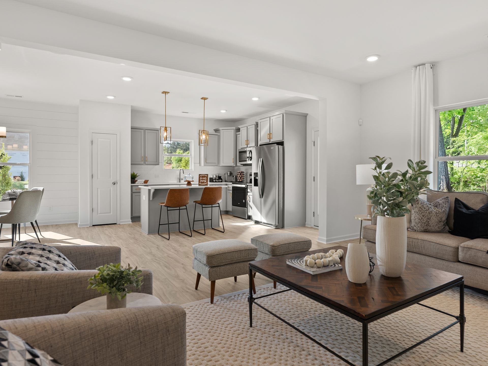 A living room with a couch , coffee table , chairs and a kitchen.