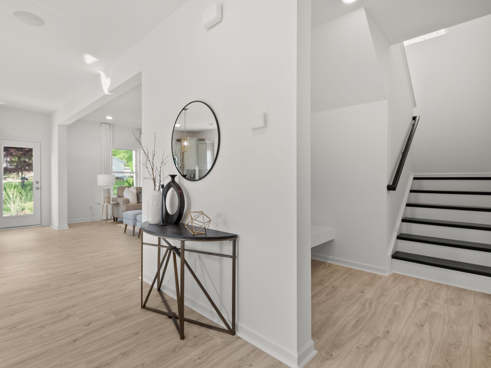 A hallway with a table , mirror and stairs in a house.