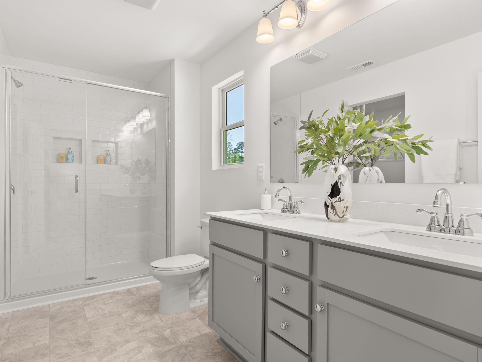 A bathroom with two sinks , a toilet , and a shower.