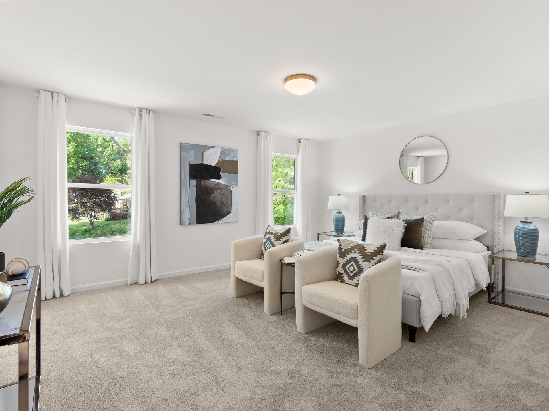 A bedroom with a bed , two chairs , lamps and a window.