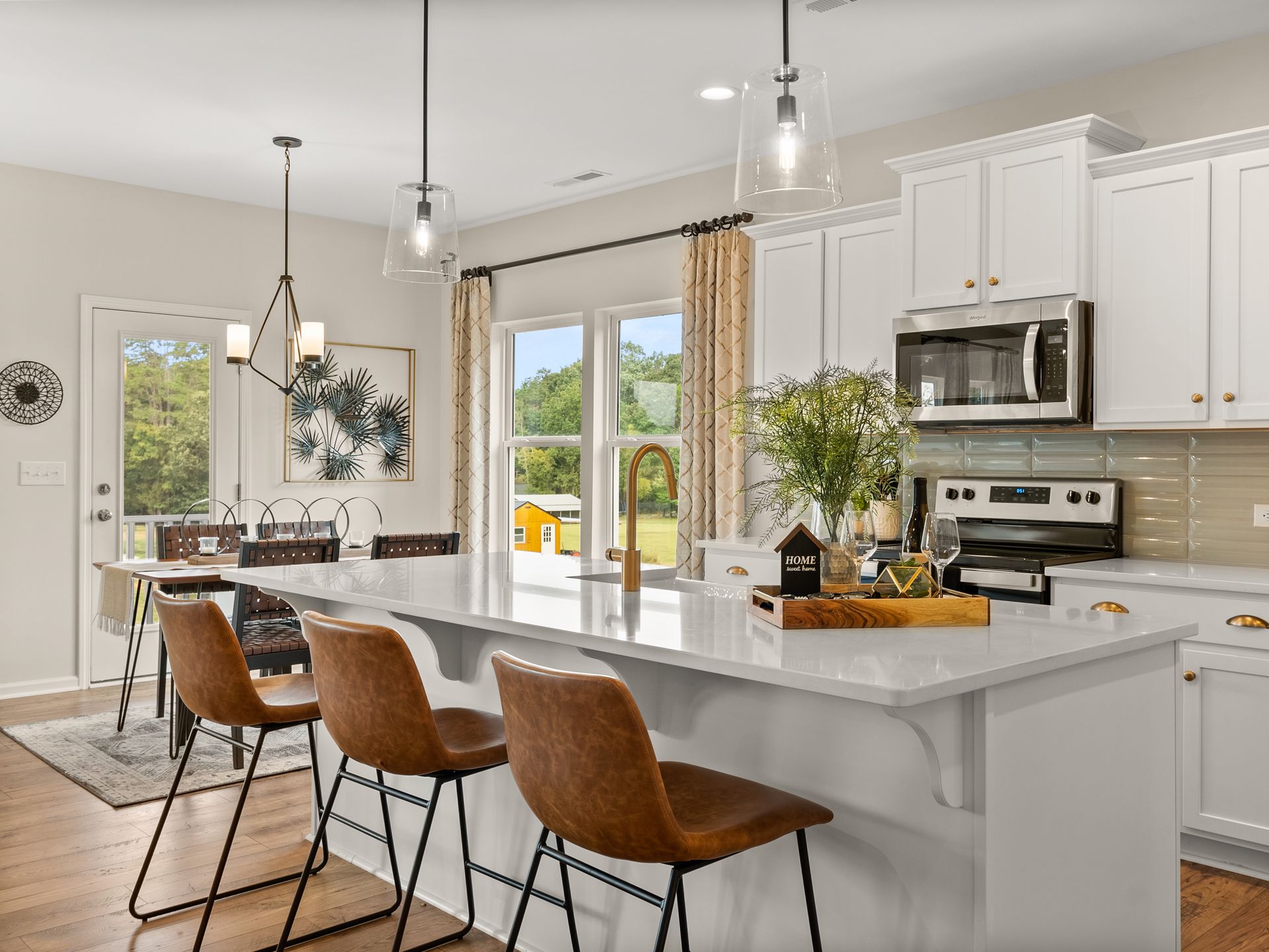 A kitchen with white cabinets , stainless steel appliances , and a large island.