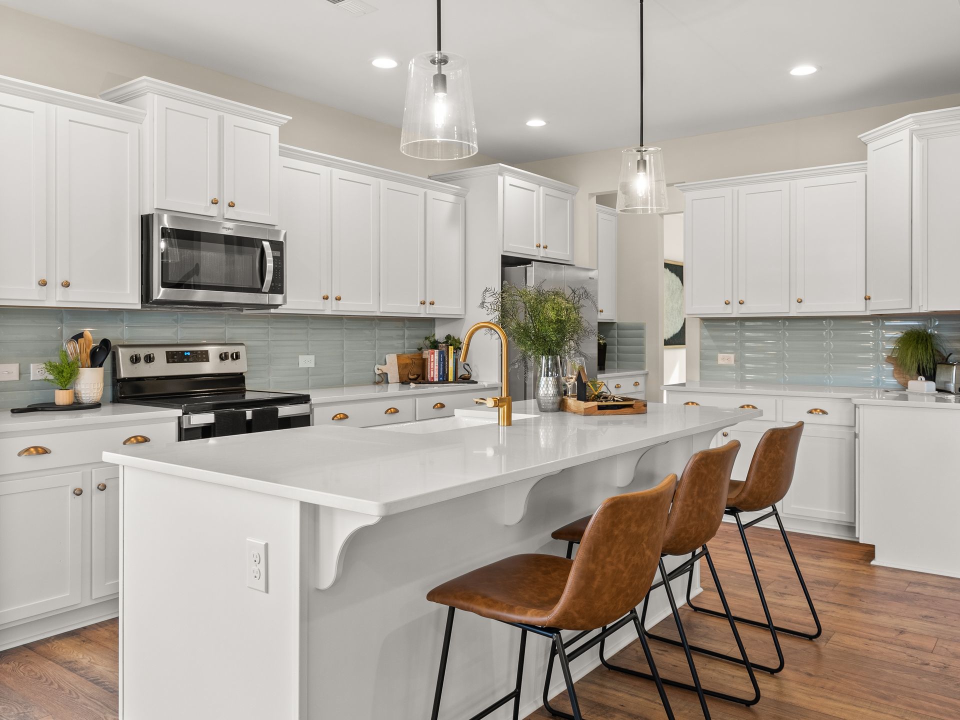 A kitchen with white cabinets , stainless steel appliances , and a large island.